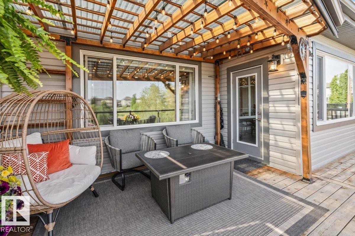 Expansive outdoor deck featuring cedar wood-decking, a clear glass railing, and a wood slat pergola - 54 Spring Gate, Spruce Grove, AB