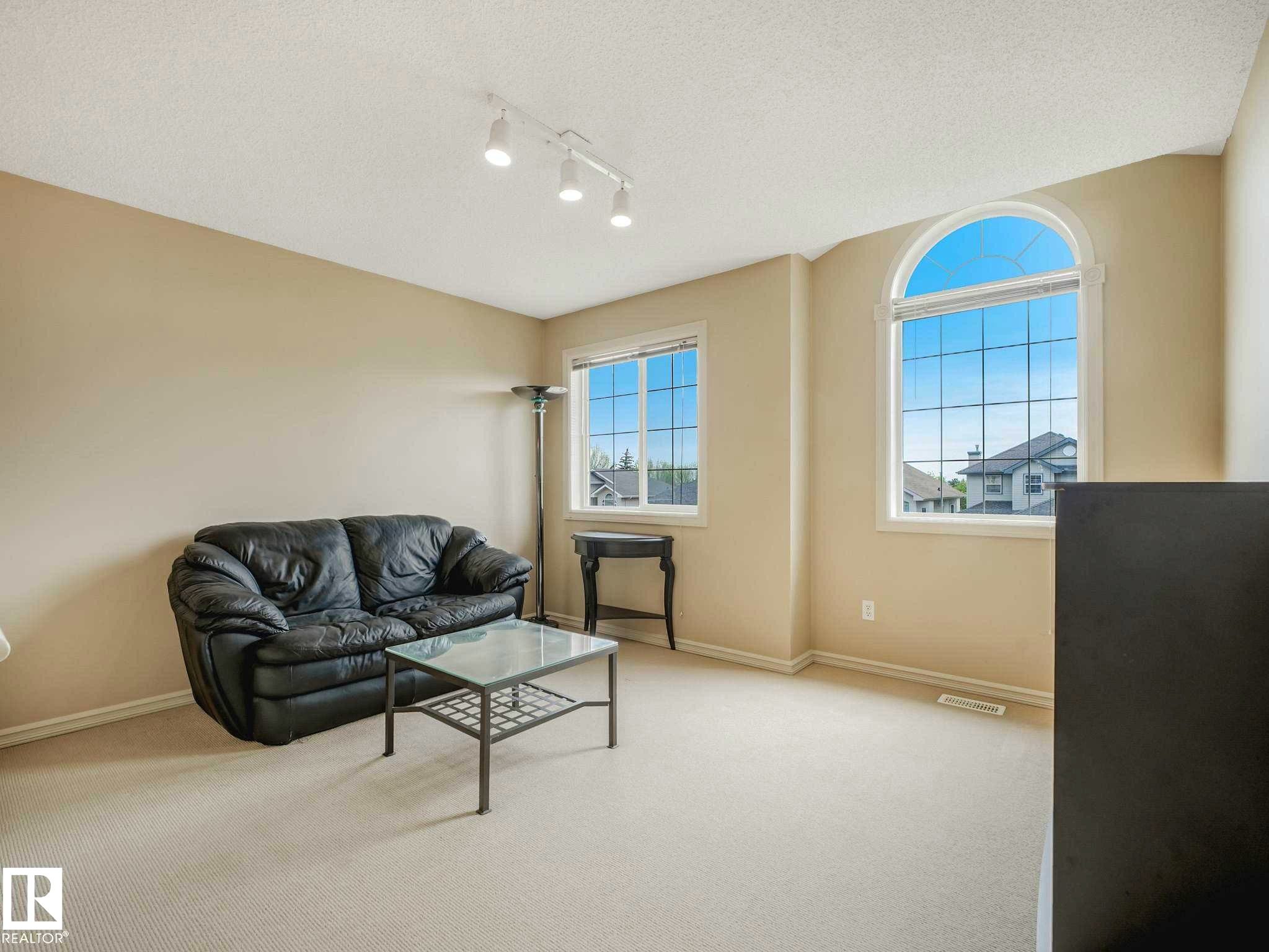 Living space featuring a large arched window and a rectangular window, light-colored walls, and track lighting - 1116 Lincoln Crescent, Edmonton, AB - Indoor Photo Showing Living Room