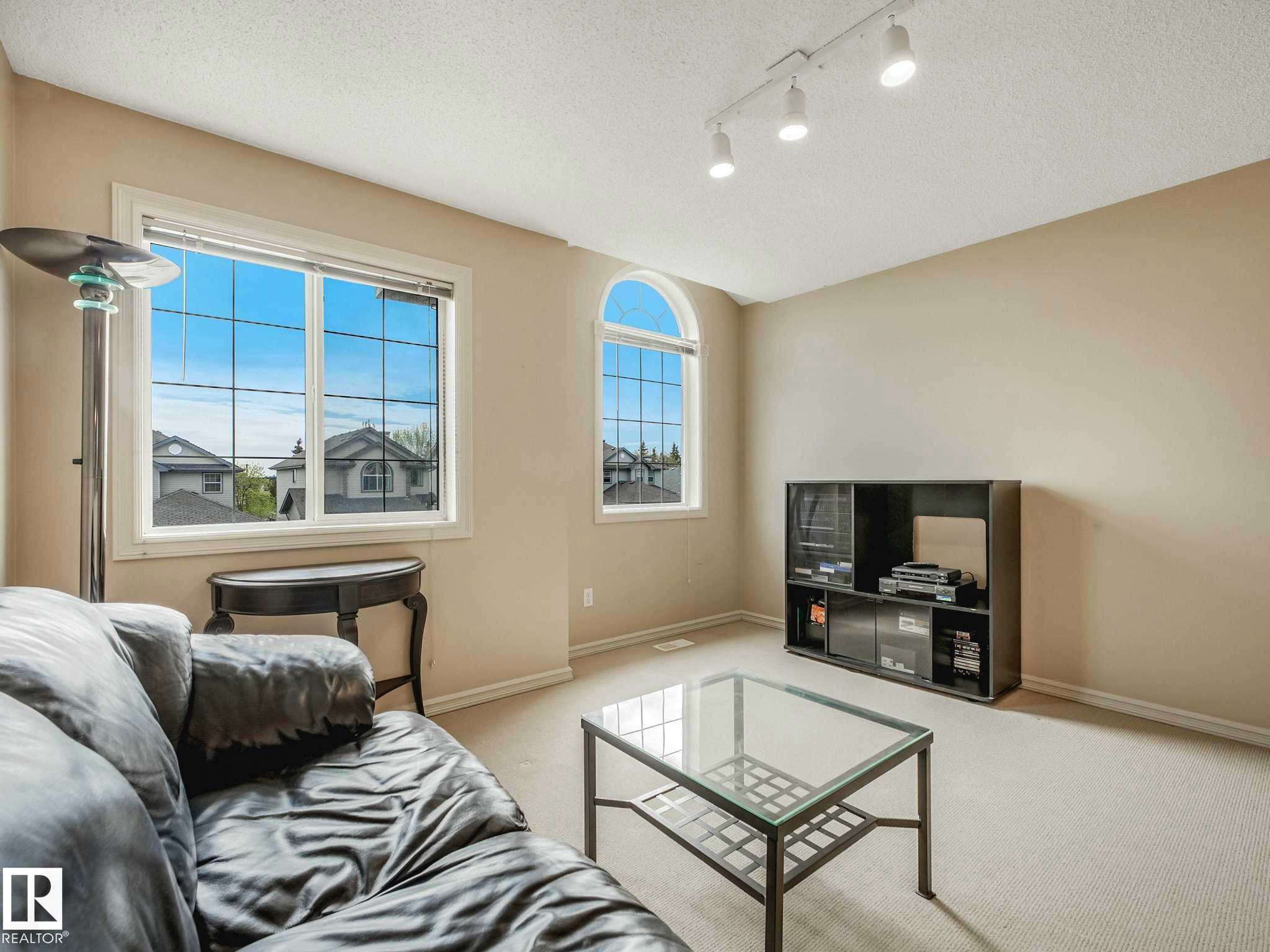 Living room with track lighting, multiple windows including an arched window, and neutral wall paint - 1116 Lincoln Crescent, Edmonton, AB - Indoor Photo Showing Living Room