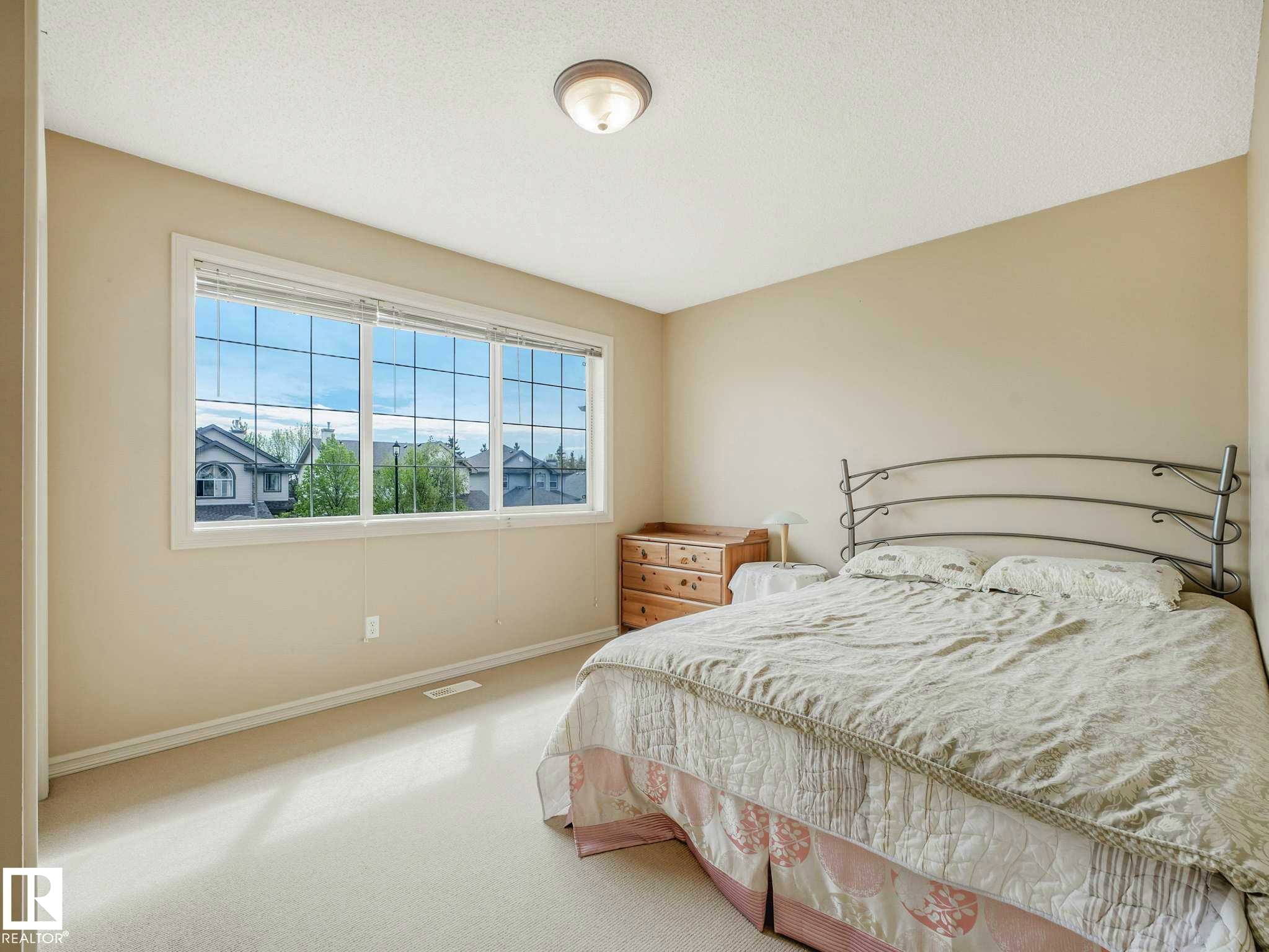 Spacious room featuring neutral carpeting, light-toned walls, and a large window with white trim - 1116 Lincoln Crescent, Edmonton, AB - Indoor Photo Showing Bedroom