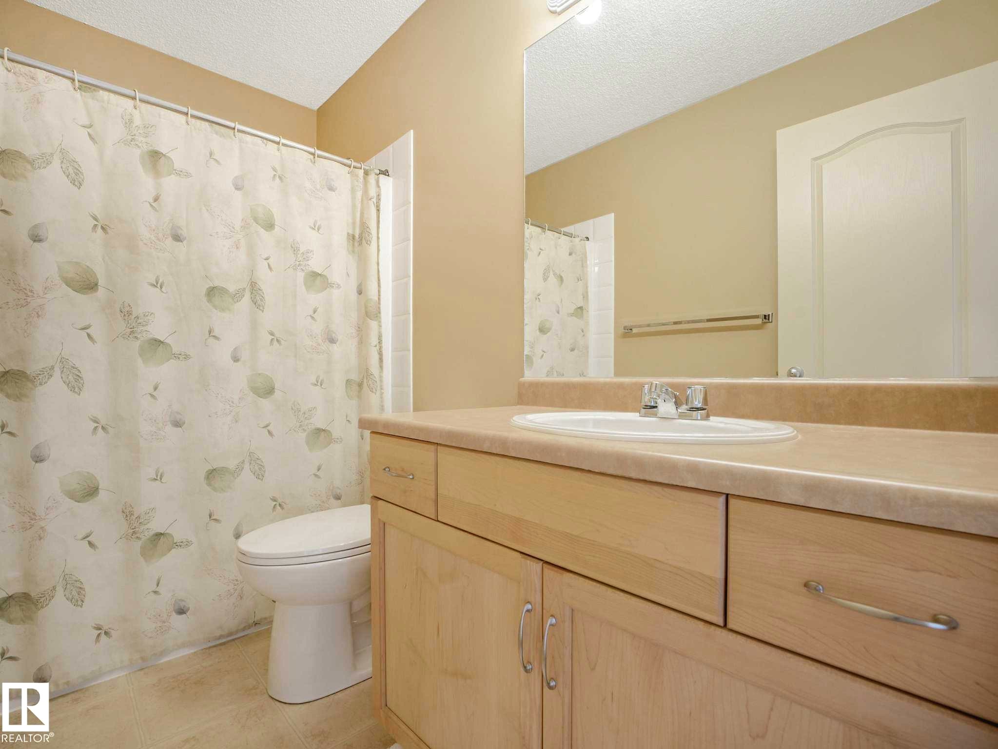 Bathroom featuring a light wood-finish vanity with an integrated sink, polished chrome faucet, and a large wall-mounted mirror - 1116 Lincoln Crescent, Edmonton, AB - Indoor Photo Showing Bathroom