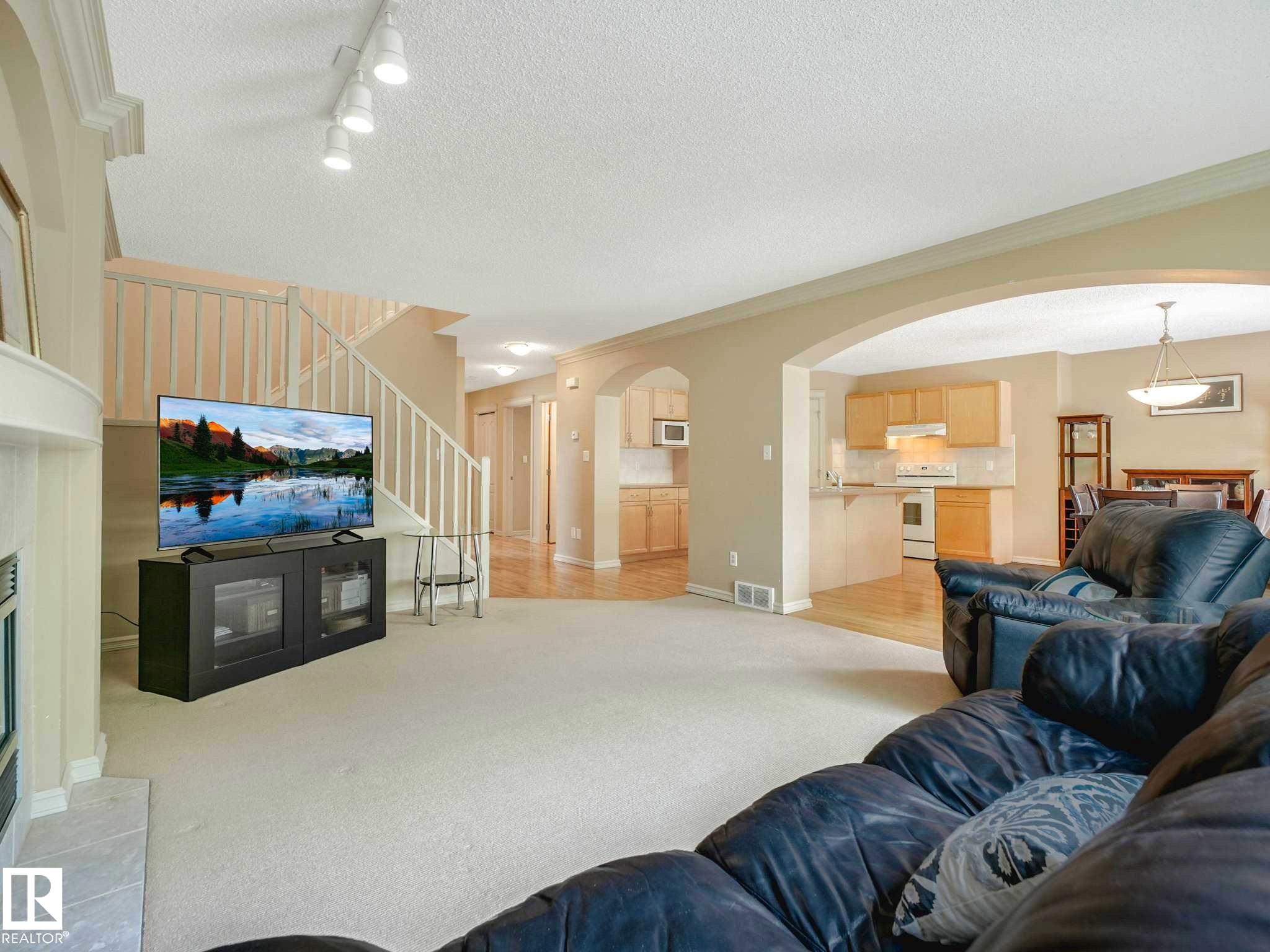 Spacious main level featuring carpet flooring, an arched doorway, and track lighting - 1116 Lincoln Crescent, Edmonton, AB - Indoor