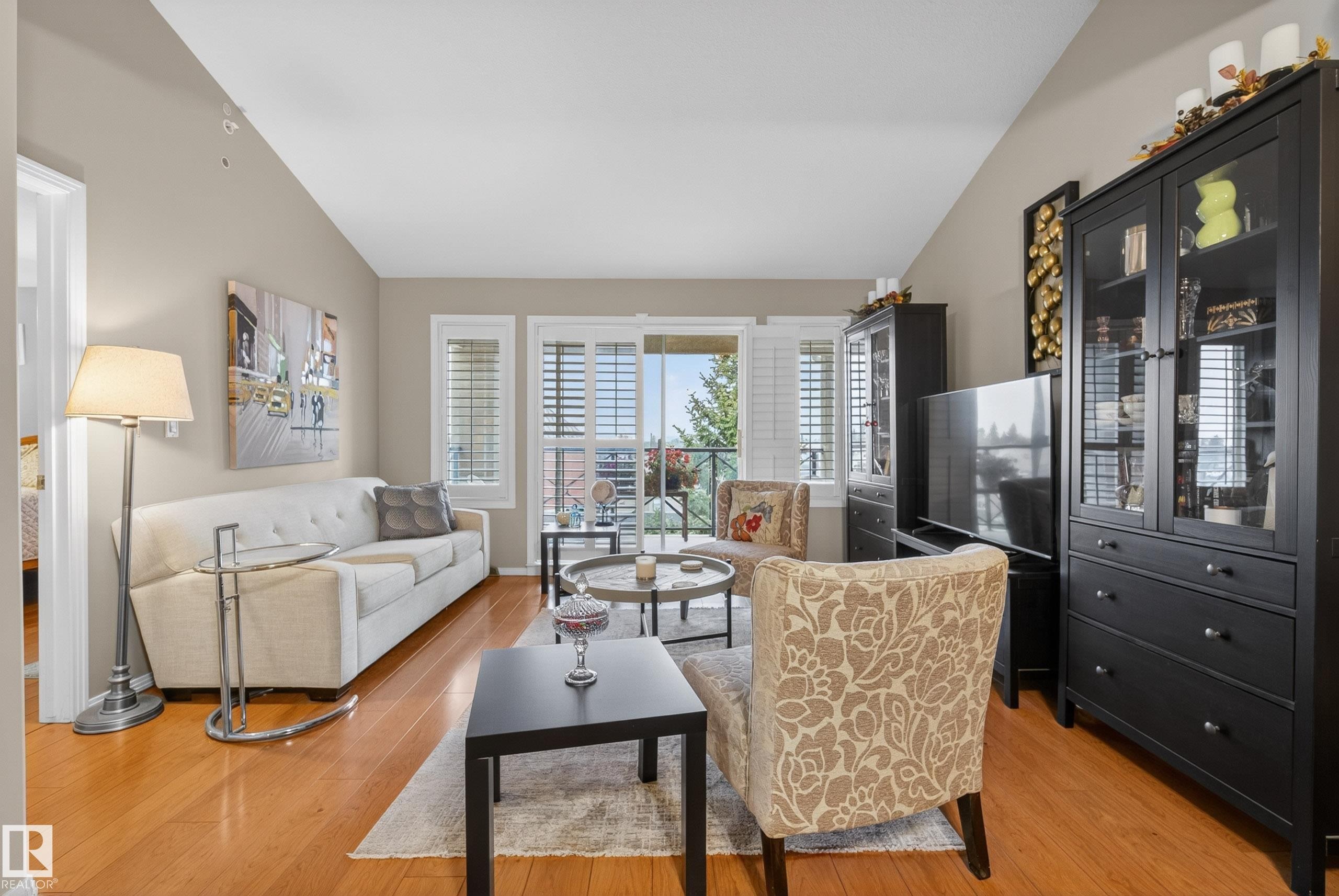 Living area with wood-finish flooring, vaulted ceilings, and neutral wall tones - 413 8912 156 Street Nw, Edmonton, AB
