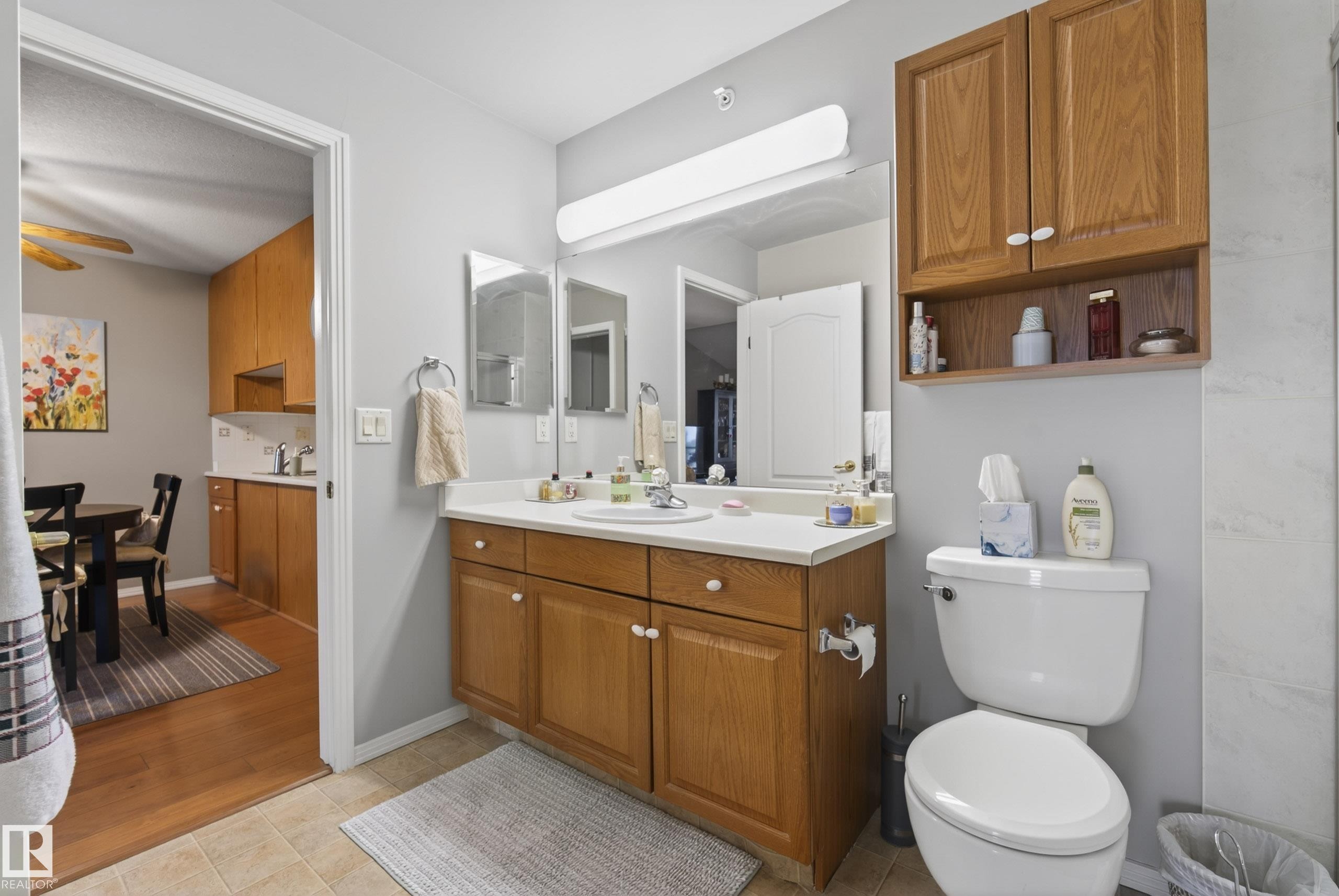 Bathroom vanity with a single sink, white countertop, and light wood-finish cabinetry - 413 8912 156 Street Nw, Edmonton, AB