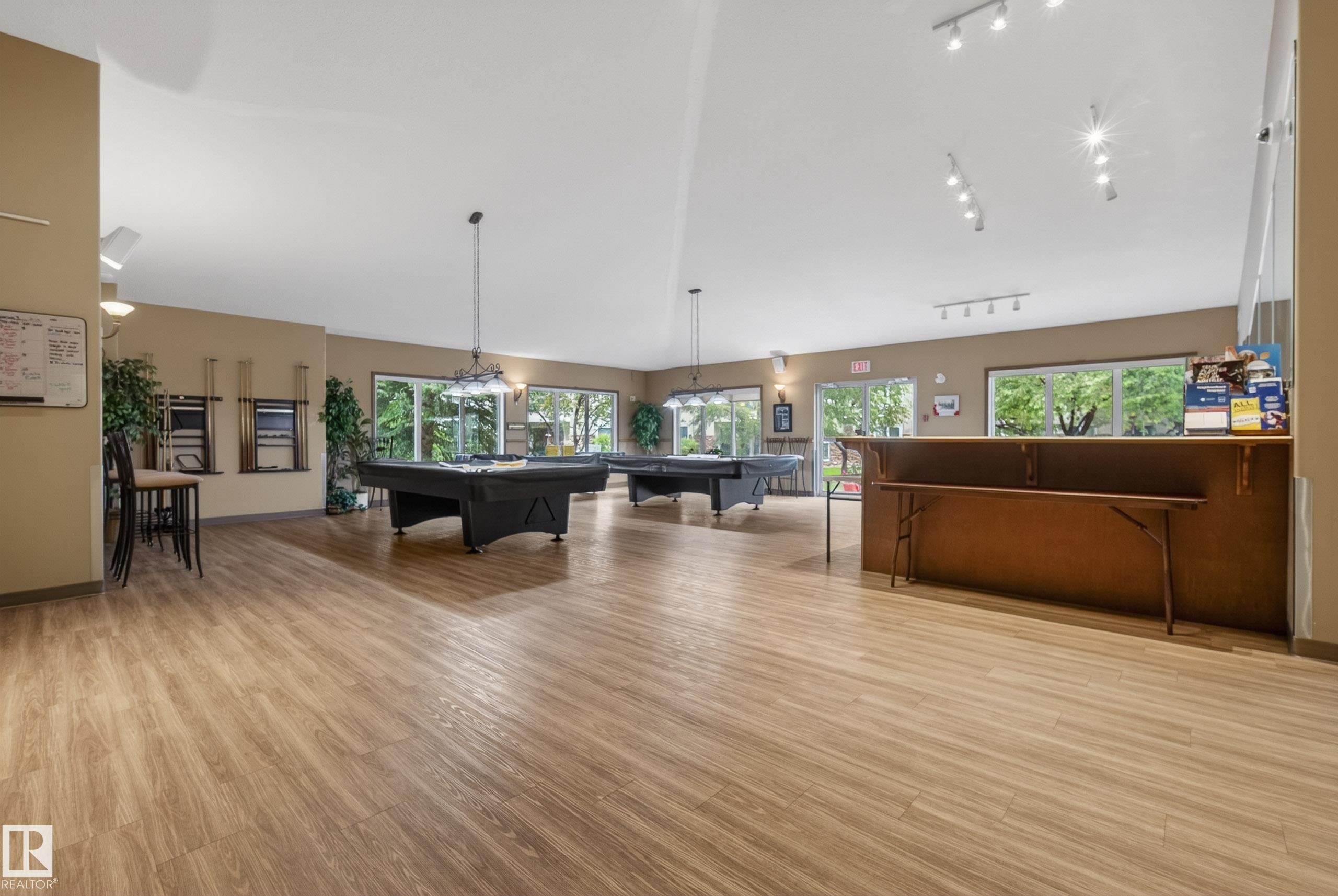 Spacious recreation room featuring wood-finish flooring and multiple recessed light fixtures - 413 8912 156 Street Nw, Edmonton, AB