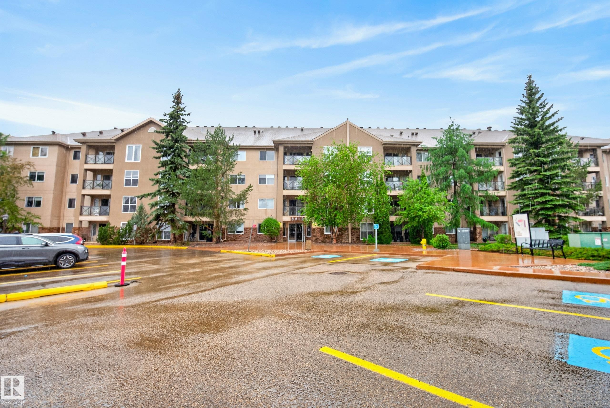 Multi-story residential building featuring a neutral-toned facade with stone accents and multiple private balconies - 413 8912 156 Street Nw, Edmonton, AB