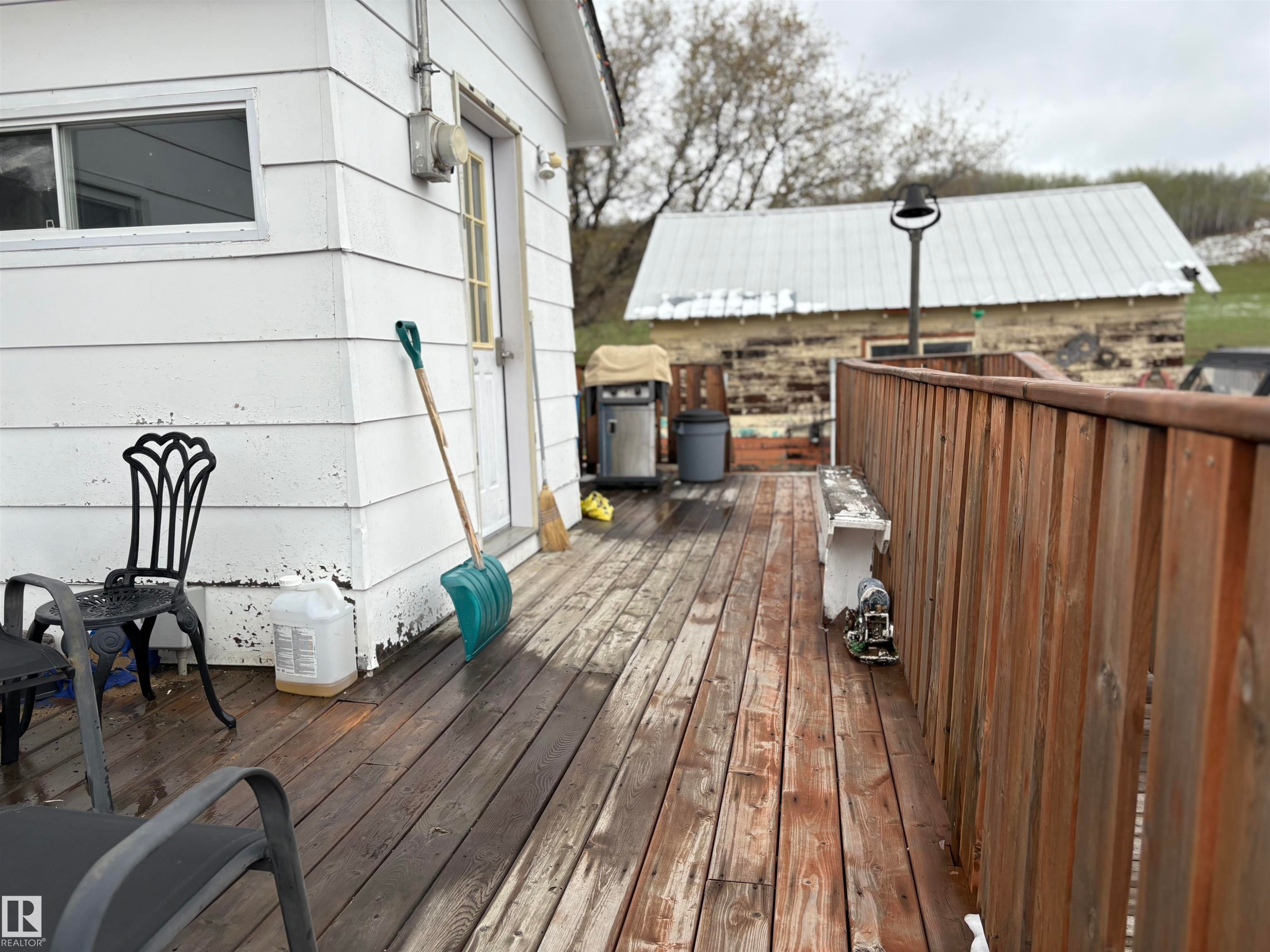 Wood-finish deck with a natural wood-tone railing and a white-painted horizontal siding exterior. - 125 56524 Rng Rd 52A, Lindbergh, AB