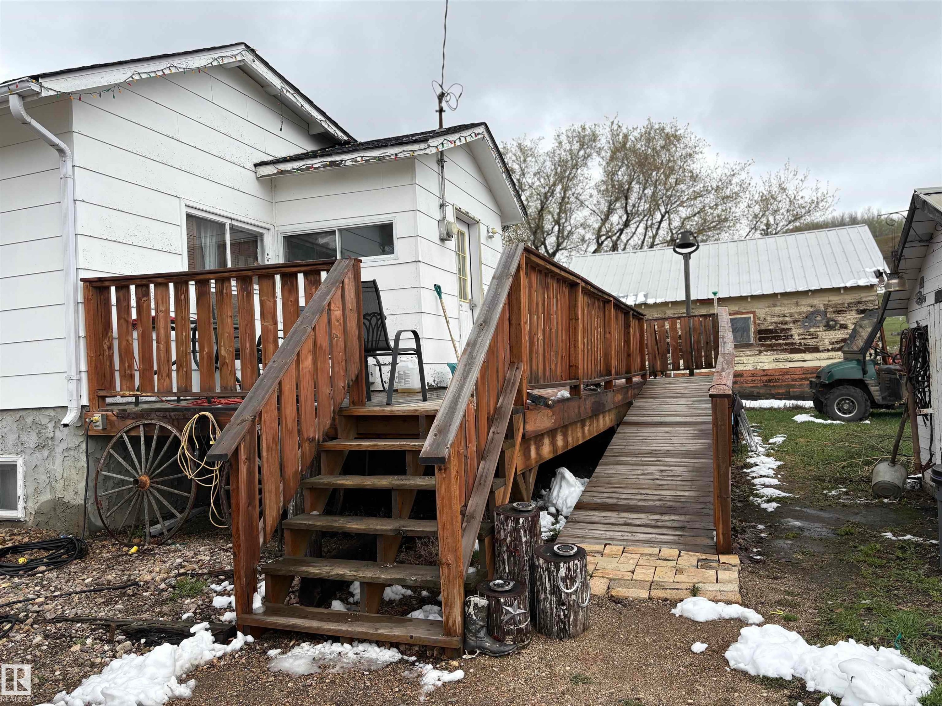 Rear exterior featuring a wood deck with railing and an accessible ramp entry - 125 56524 Rng Rd 52A, Lindbergh, AB