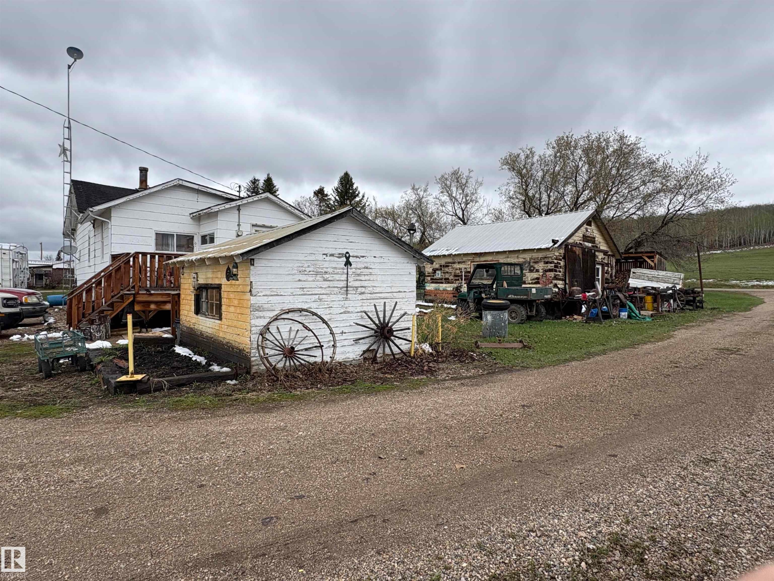 Property featuring multiple outbuildings, including a white-sided structure with a pitched roof and a log building with a metal roof. - 125 56524 Rng Rd 52A, Lindbergh, AB