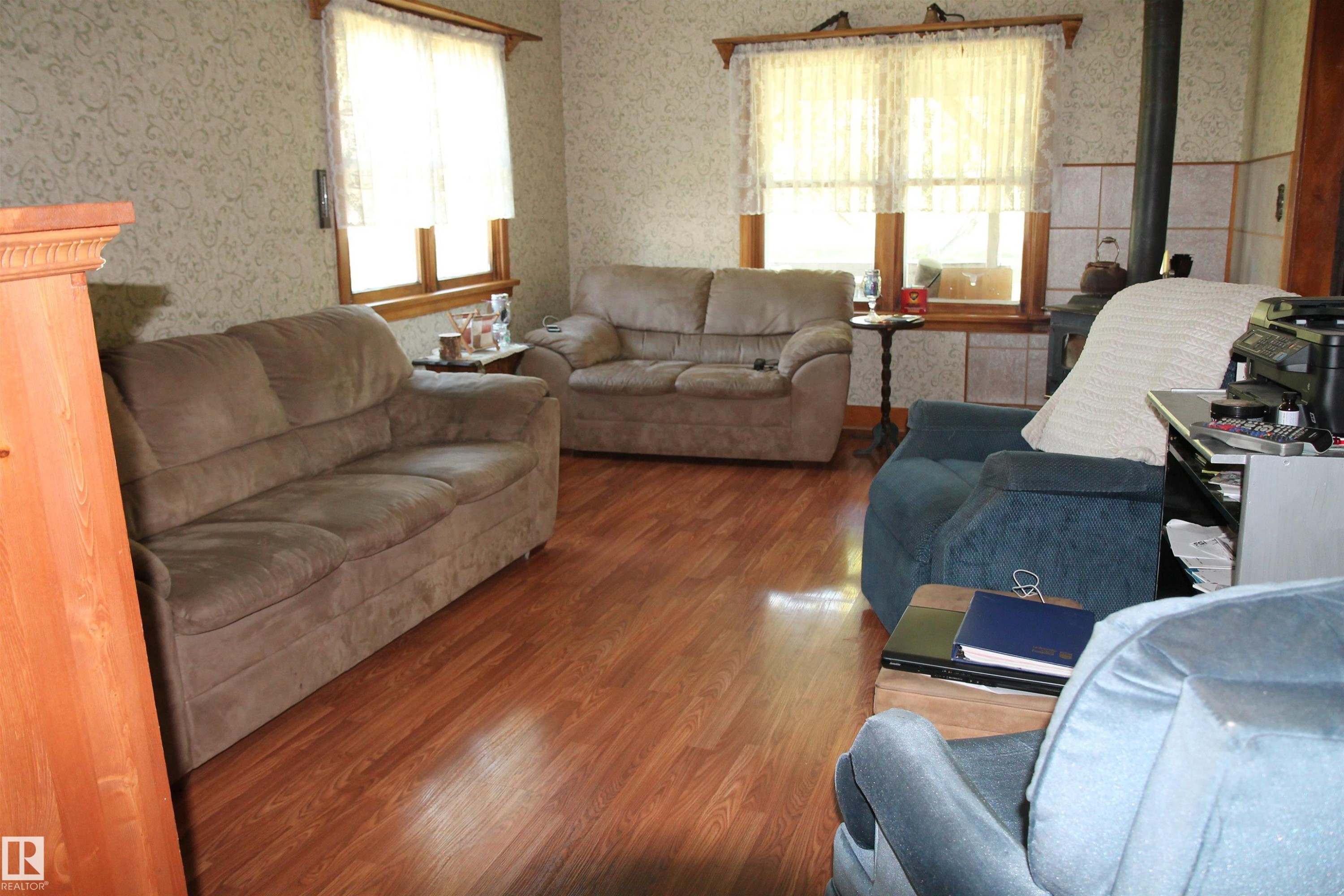 Room featuring wood-finish flooring, patterned wallpaper, and multiple windows with wood trim. - 125 56524 Rng Rd 52A, Lindbergh, AB