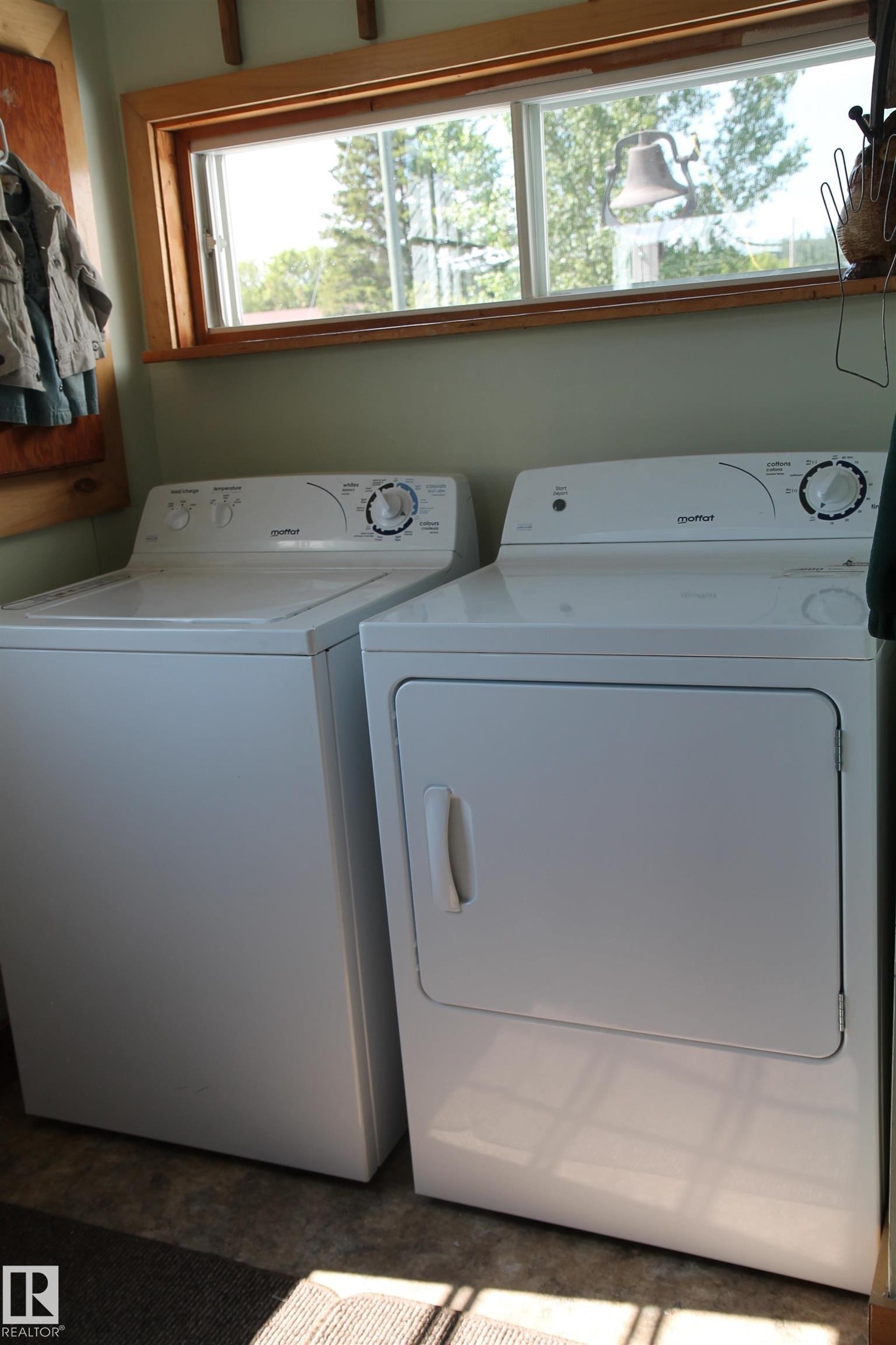 Dedicated laundry area featuring a white washing machine, white dryer, and an overhead window with natural wood trim. - 125 56524 Rng Rd 52A, Lindbergh, AB