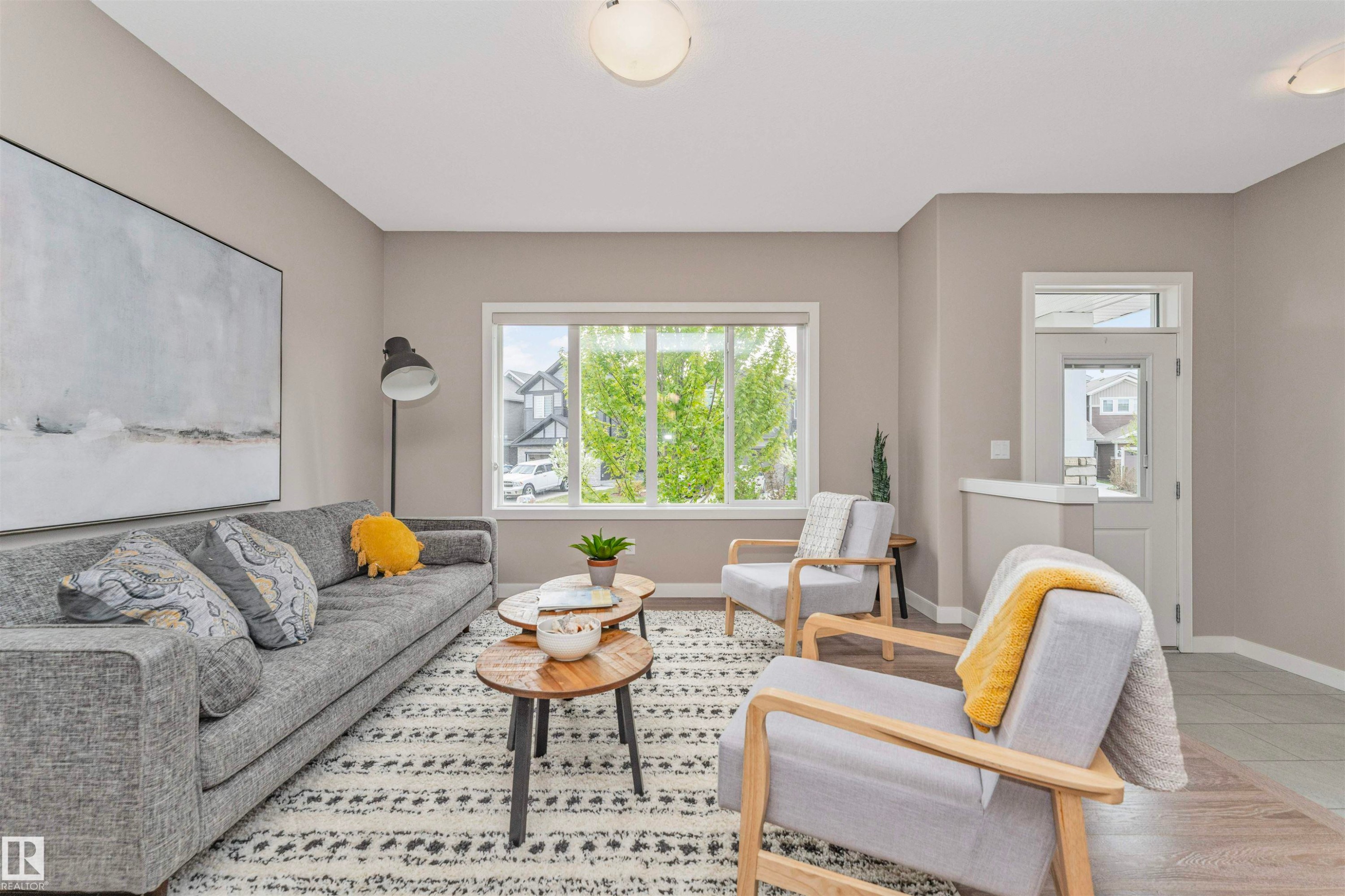 Living area featuring neutral wall paint, wood-finish flooring, and a large window with white trim - 22124 85 Avenue Nw, Edmonton, AB - Indoor Photo Showing Living Room