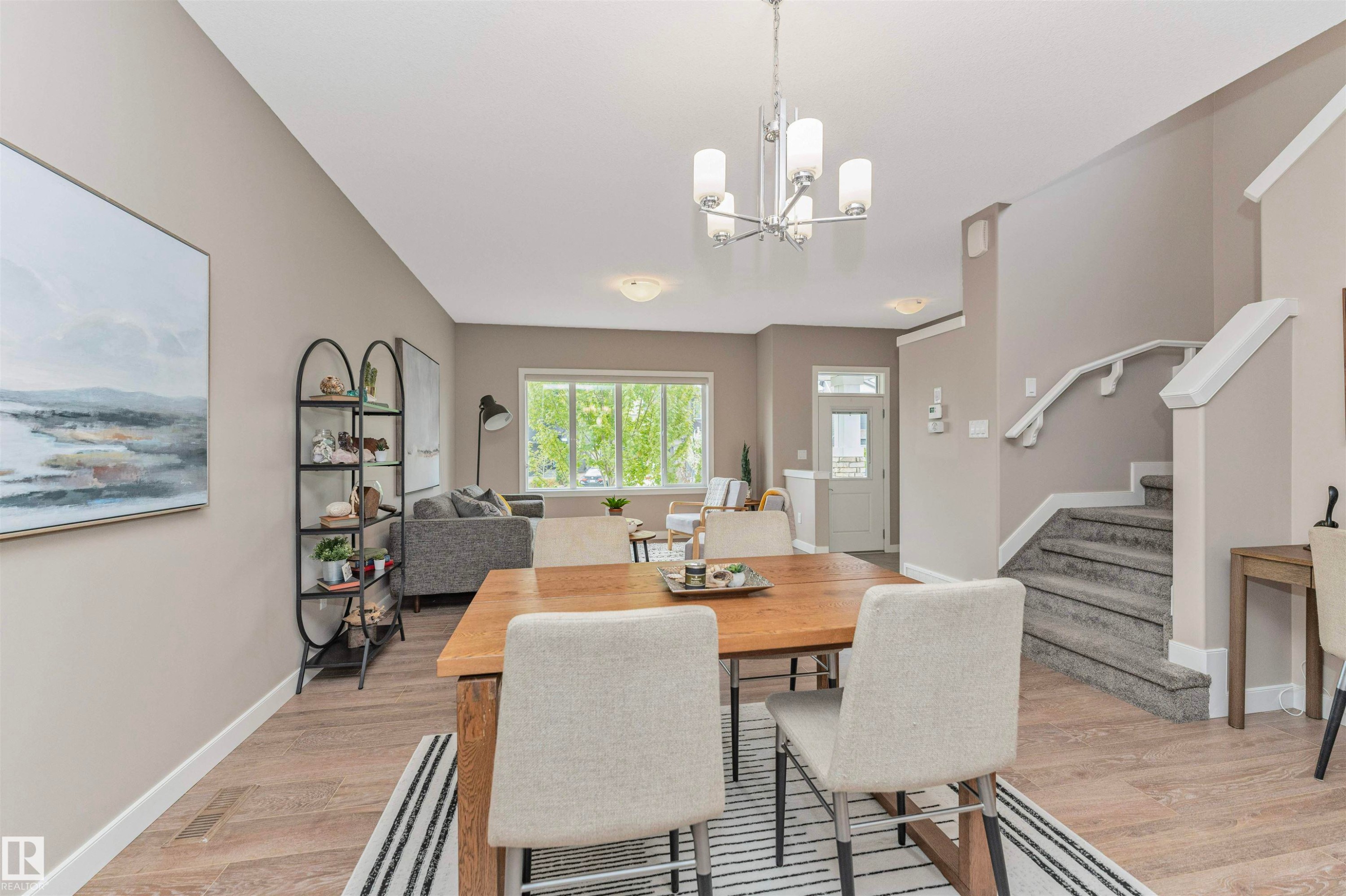 Open-concept living area featuring wood-finish flooring, a contemporary chandelier, and large windows - 22124 85 Avenue Nw, Edmonton, AB - Indoor Photo Showing Dining Room