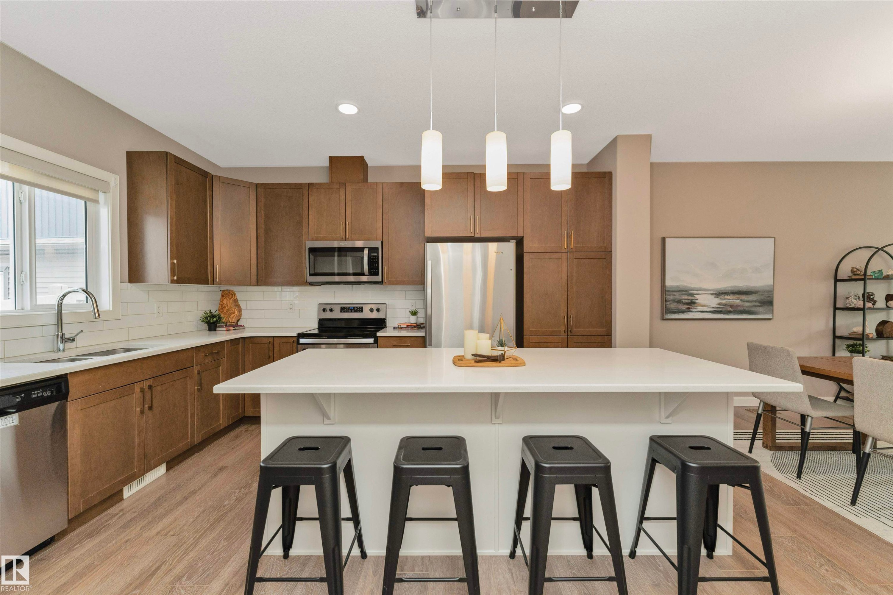 Kitchen featuring wood-finish cabinetry, stainless steel appliances, a white subway tile backsplash, a large center island with a white countertop, and wood-finish flooring - 22124 85 Avenue Nw, Edmonton, AB - Indoor Photo Showing Kitchen With Stainless Steel Kitchen With Double Sink With Upgraded Kitchen