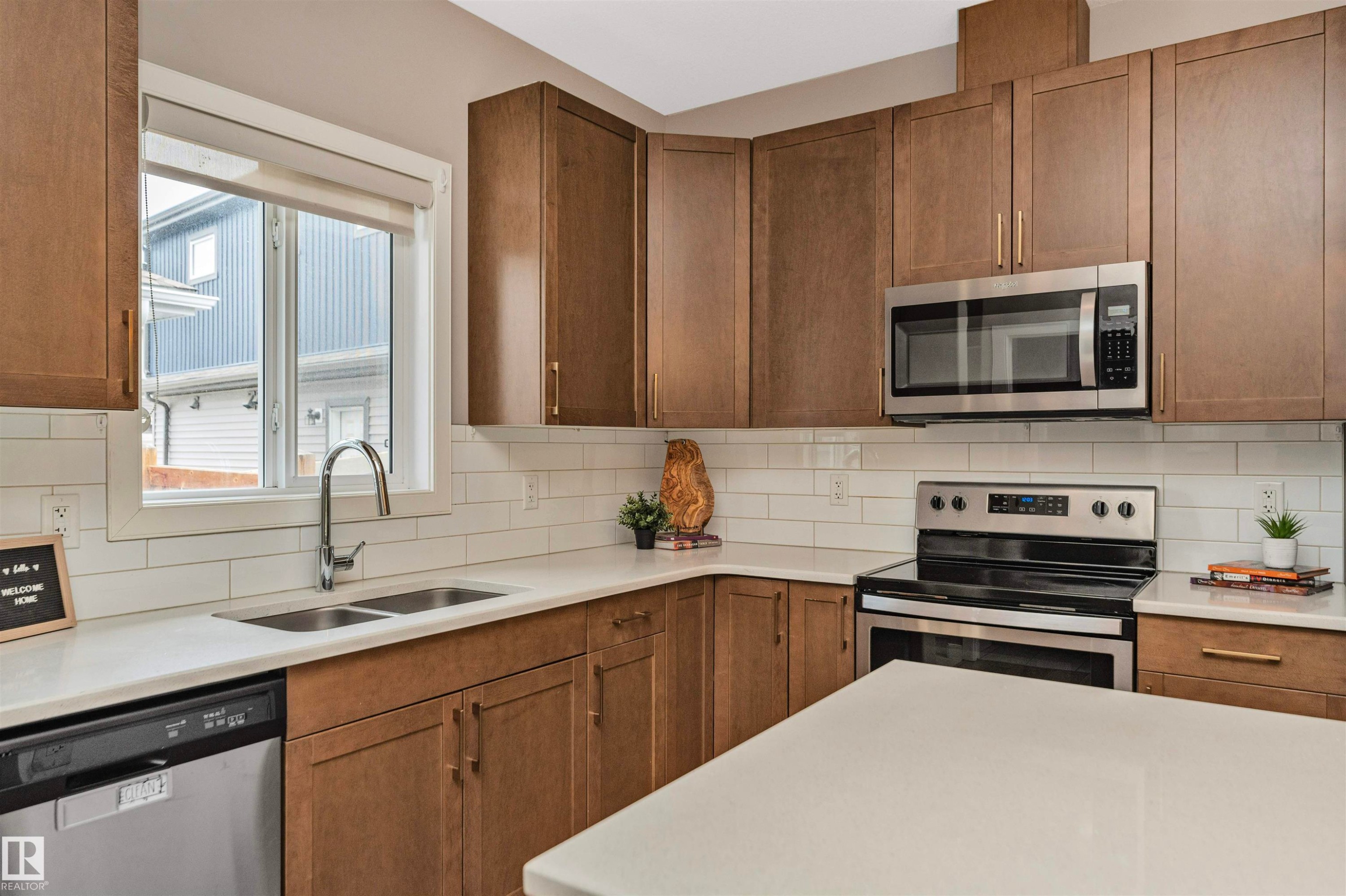 Kitchen featuring wood-finish cabinetry, white subway tile backsplash, and light-toned countertops - 22124 85 Avenue Nw, Edmonton, AB - Indoor Photo Showing Kitchen With Stainless Steel Kitchen With Double Sink