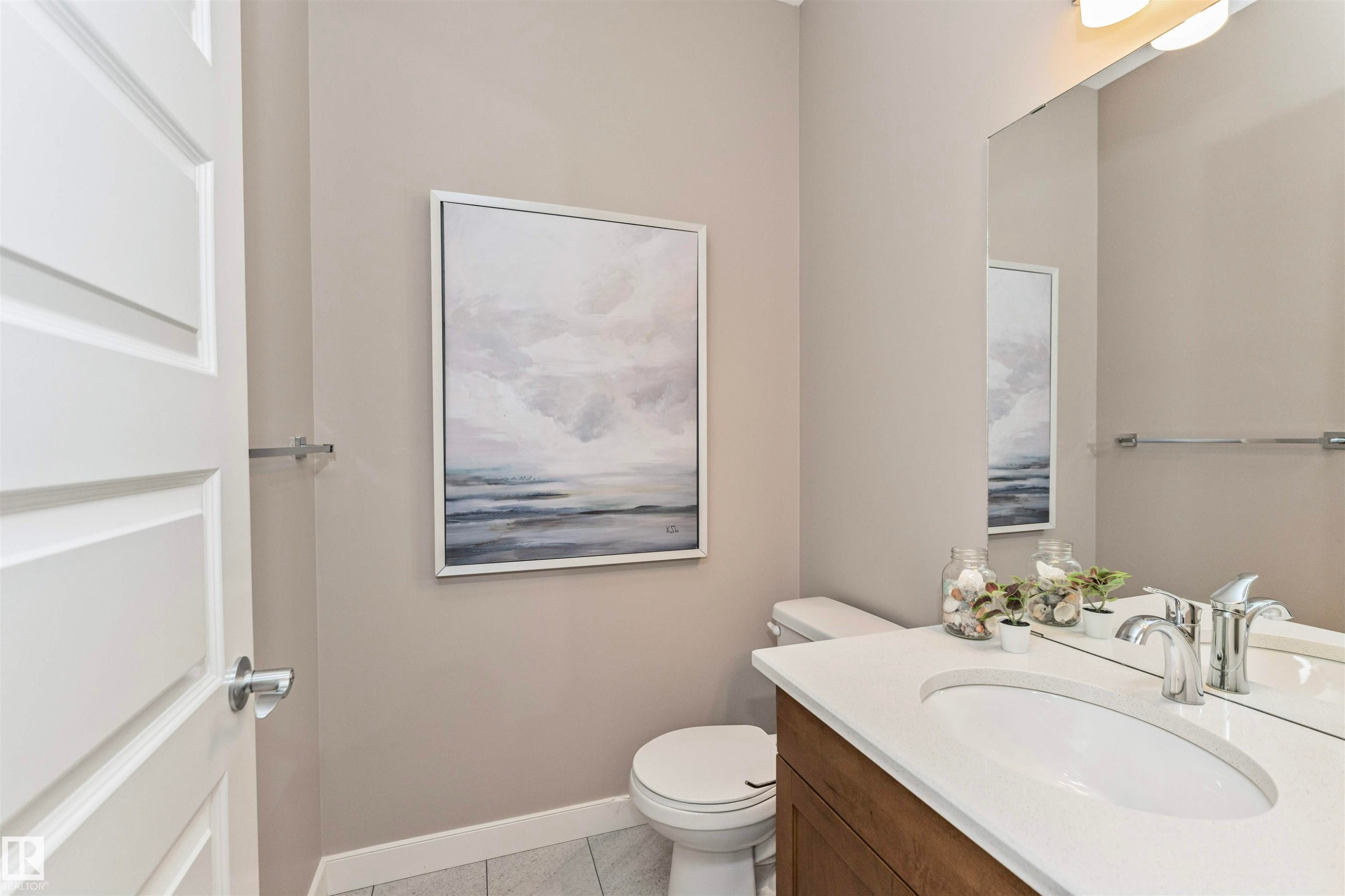 Half bath featuring a wood-finish vanity with an integrated white sink, chrome faucet, and expansive wall-mounted mirror - 22124 85 Avenue Nw, Edmonton, AB - Indoor Photo Showing Bathroom