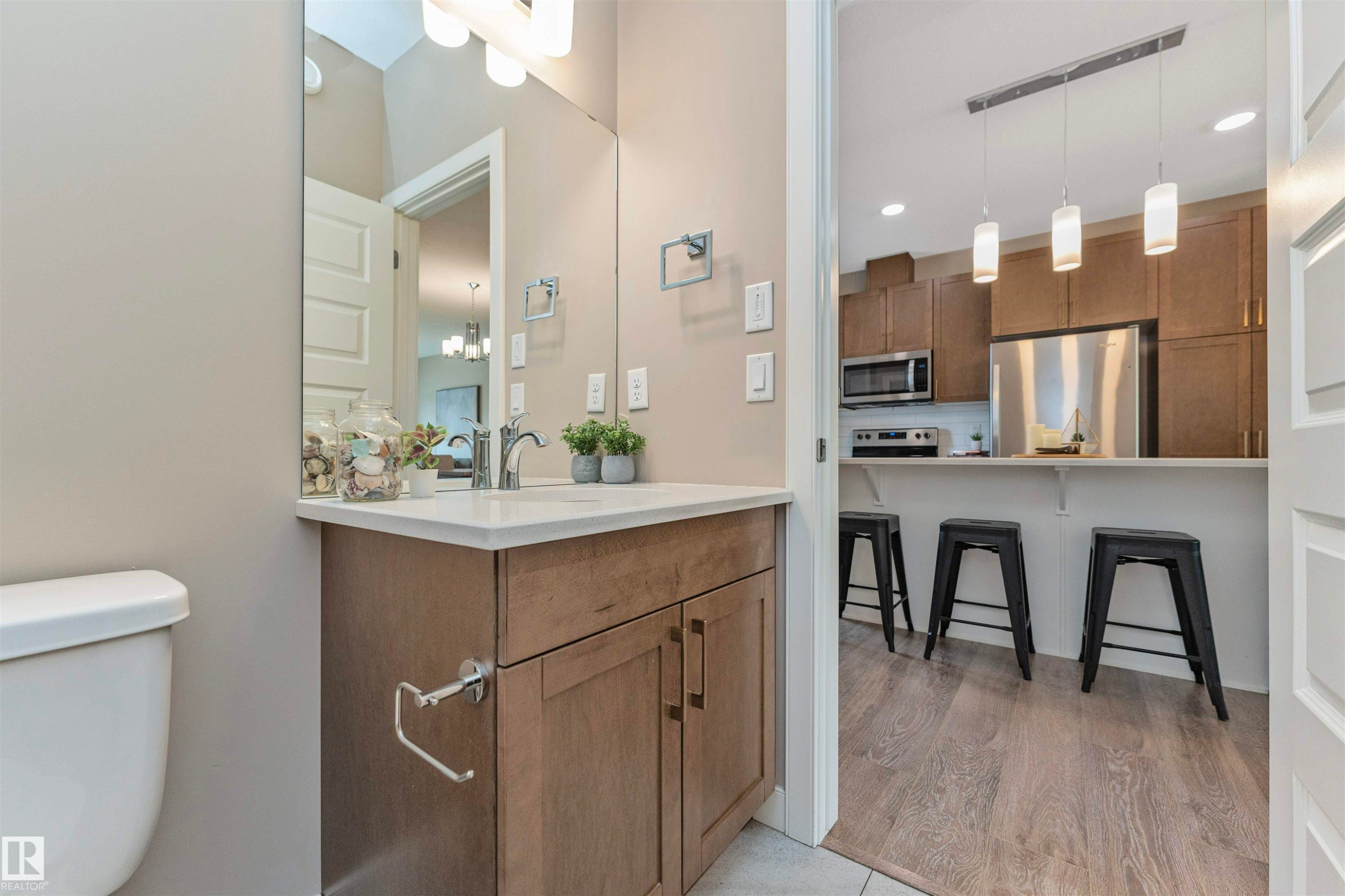Bathroom vanity with a white countertop, chrome faucet, and wood-finish cabinetry - 22124 85 Avenue Nw, Edmonton, AB - Indoor Photo Showing Bathroom