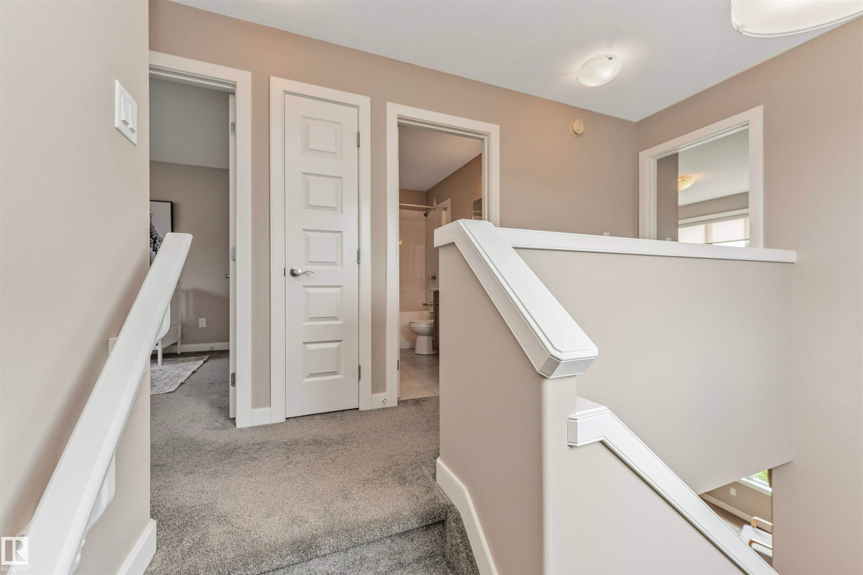 Carpeted staircase and landing with light gray walls, white trim, white paneled doors, and a ceiling-mounted light fixture - 22124 85 Avenue Nw, Edmonton, AB - Indoor Photo Showing Other Room