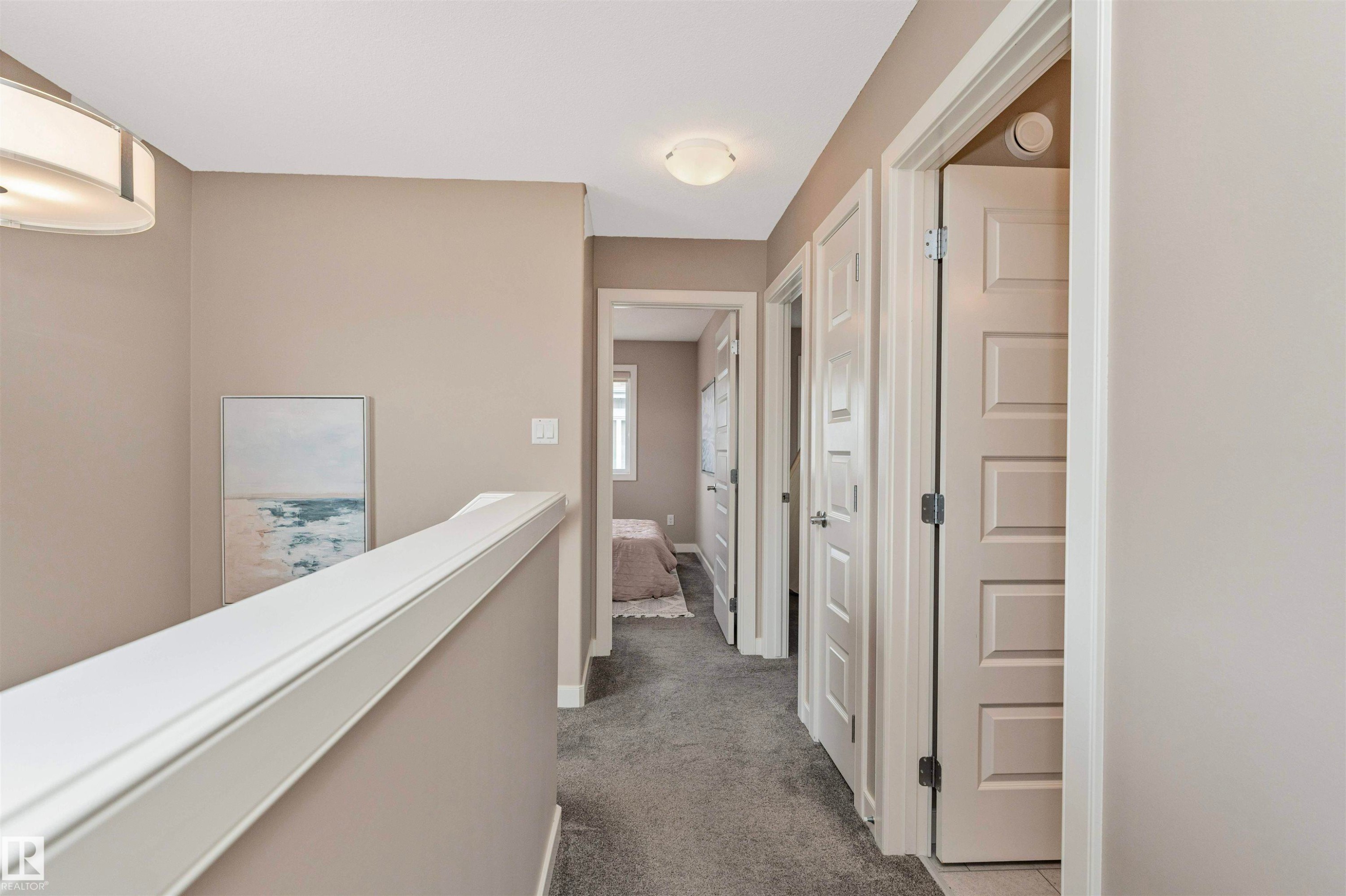 Upper-level hallway featuring neutral wall tones, gray carpet, multiple paneled doors, and a decorative railing - 22124 85 Avenue Nw, Edmonton, AB - Indoor Photo Showing Other Room