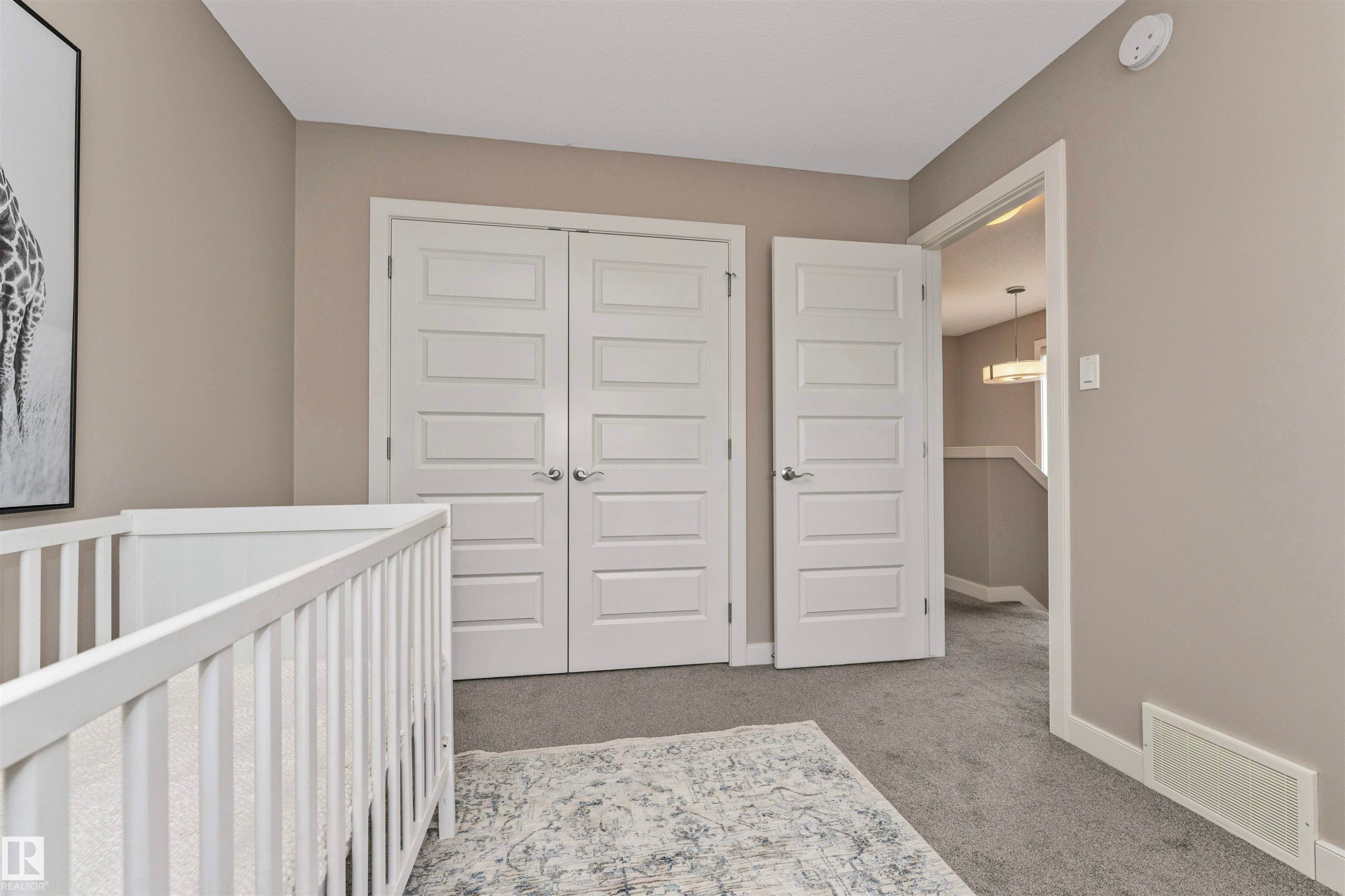 Neutral-toned wall paint with white trim, contemporary five-panel interior doors, plush gray carpeting, and a white ceiling-mounted smoke detector - 22124 85 Avenue Nw, Edmonton, AB - Indoor Photo Showing Other Room