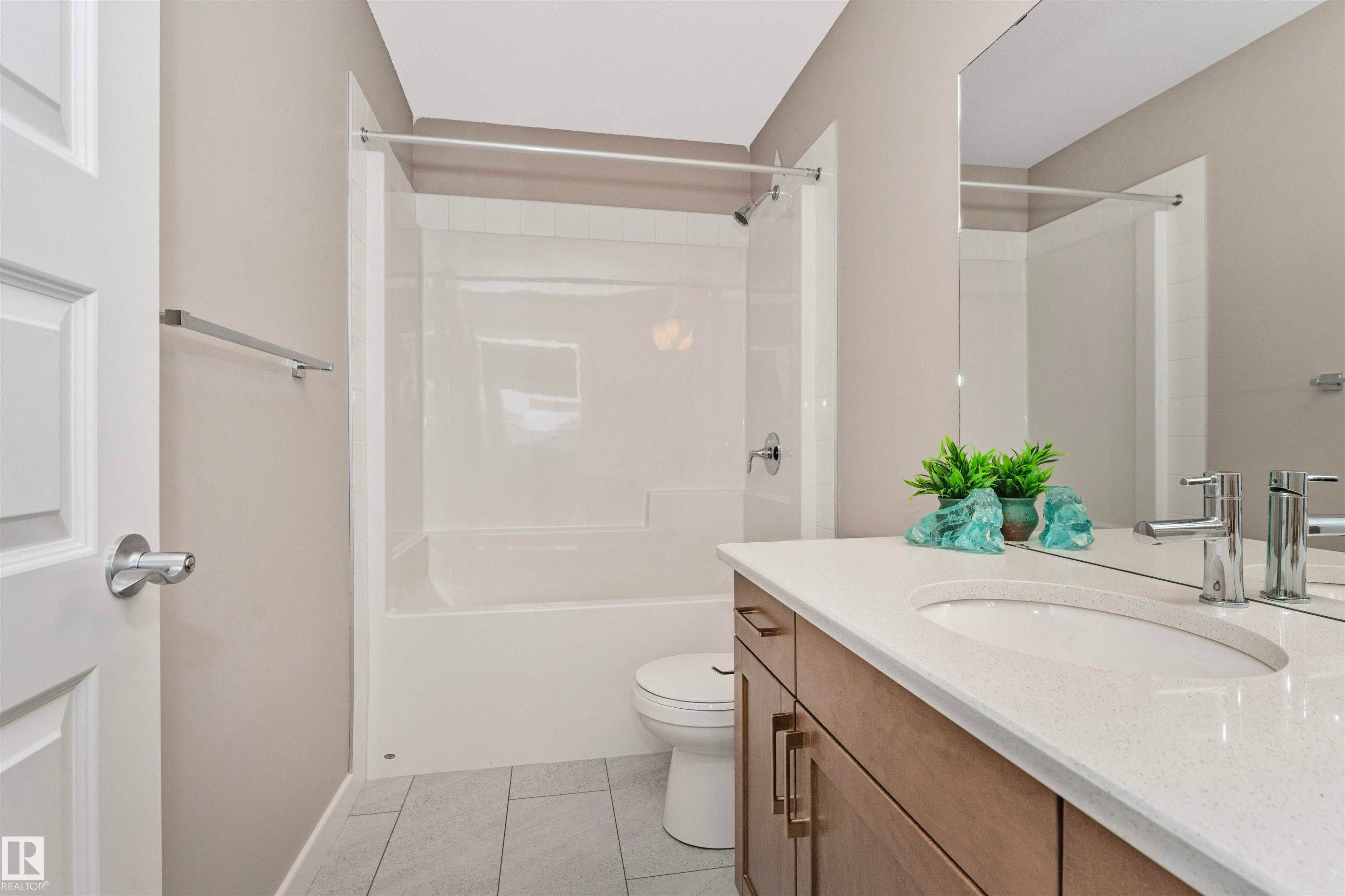 Bathroom featuring a wood-finish vanity with a light-toned countertop, an integrated sink, and chrome fixtures - 22124 85 Avenue Nw, Edmonton, AB - Indoor Photo Showing Bathroom