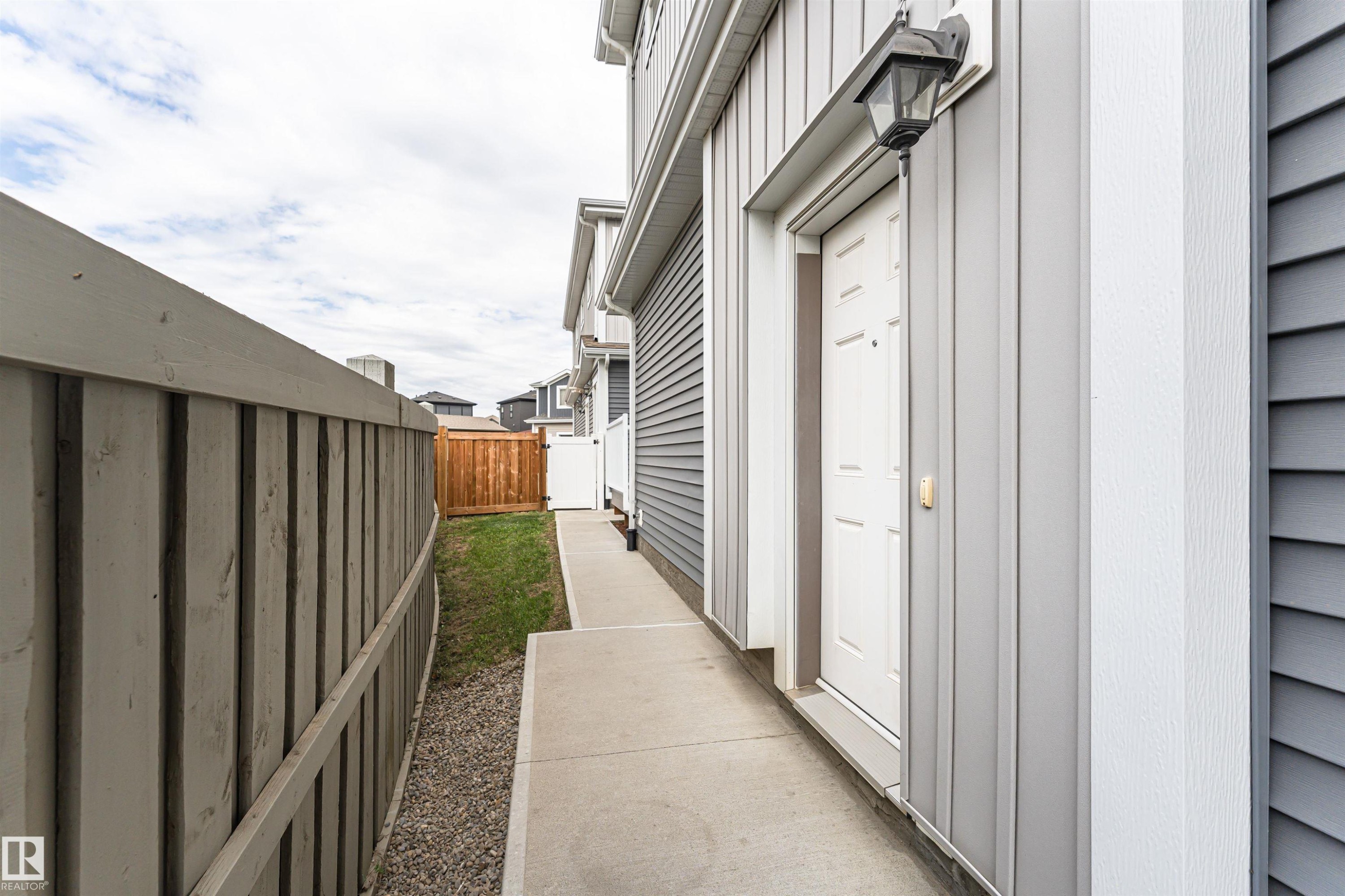 Side entrance with a white panel door and exterior lantern lighting - 22124 85 Avenue Nw, Edmonton, AB - Outdoor With Exterior