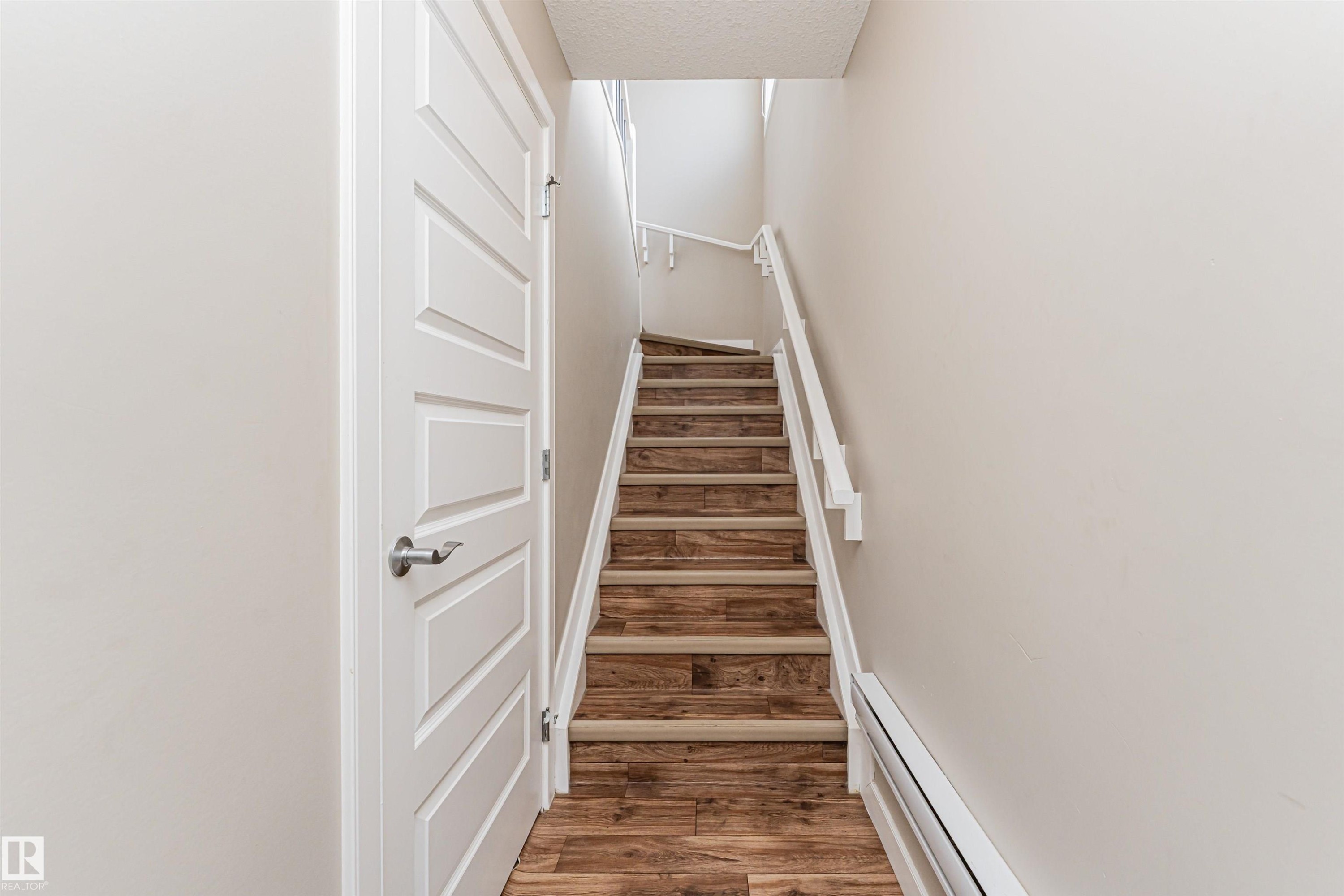 Staircase featuring wood-finish treads and risers, white painted handrails, and neutral wall tones - 22124 85 Avenue Nw, Edmonton, AB - Indoor Photo Showing Other Room