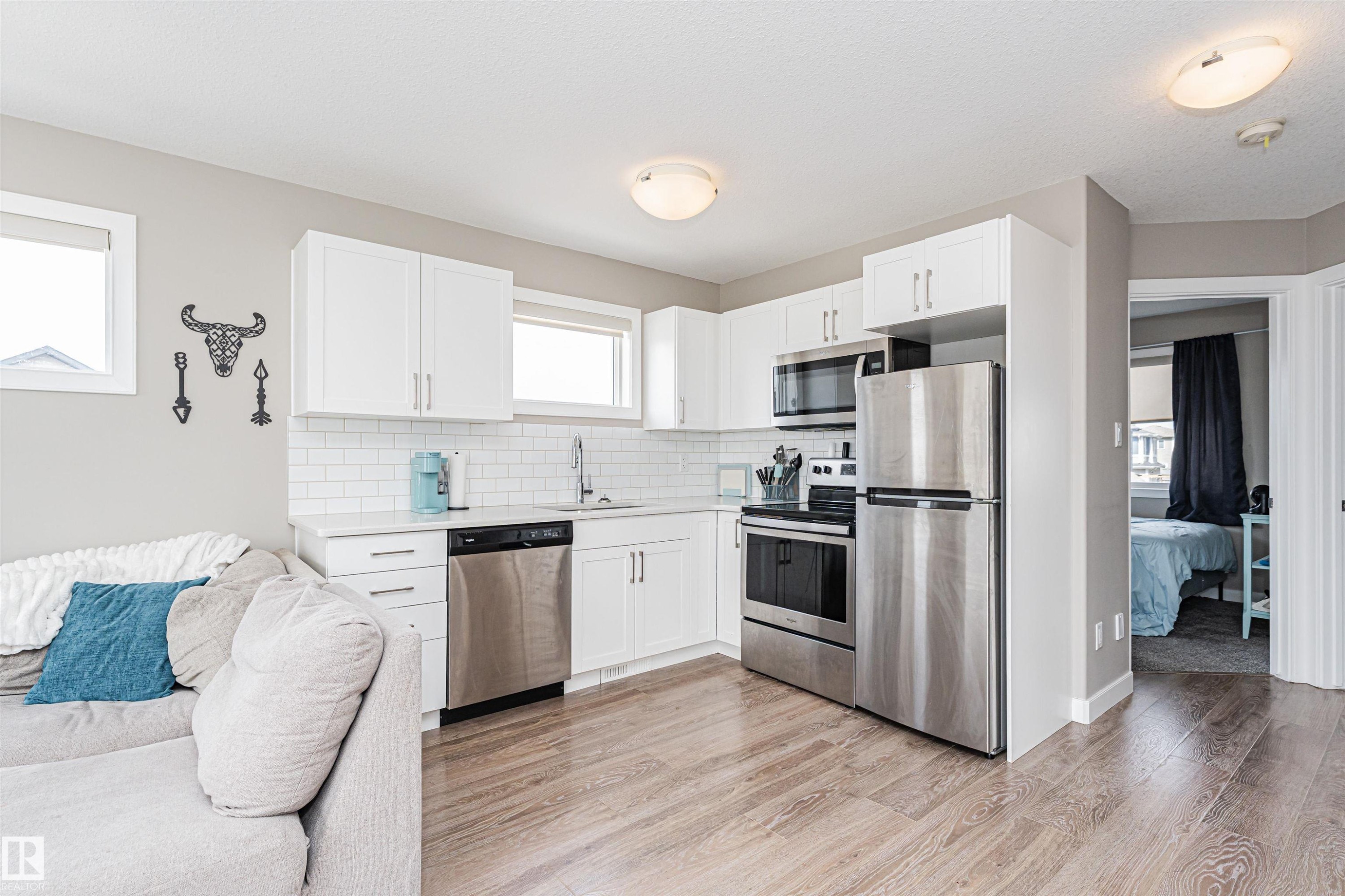 Kitchen featuring white shaker-style cabinetry, stainless steel appliances, white subway tile backsplash, and light wood-finish flooring - 22124 85 Avenue Nw, Edmonton, AB - Indoor Photo Showing Kitchen With Stainless Steel Kitchen