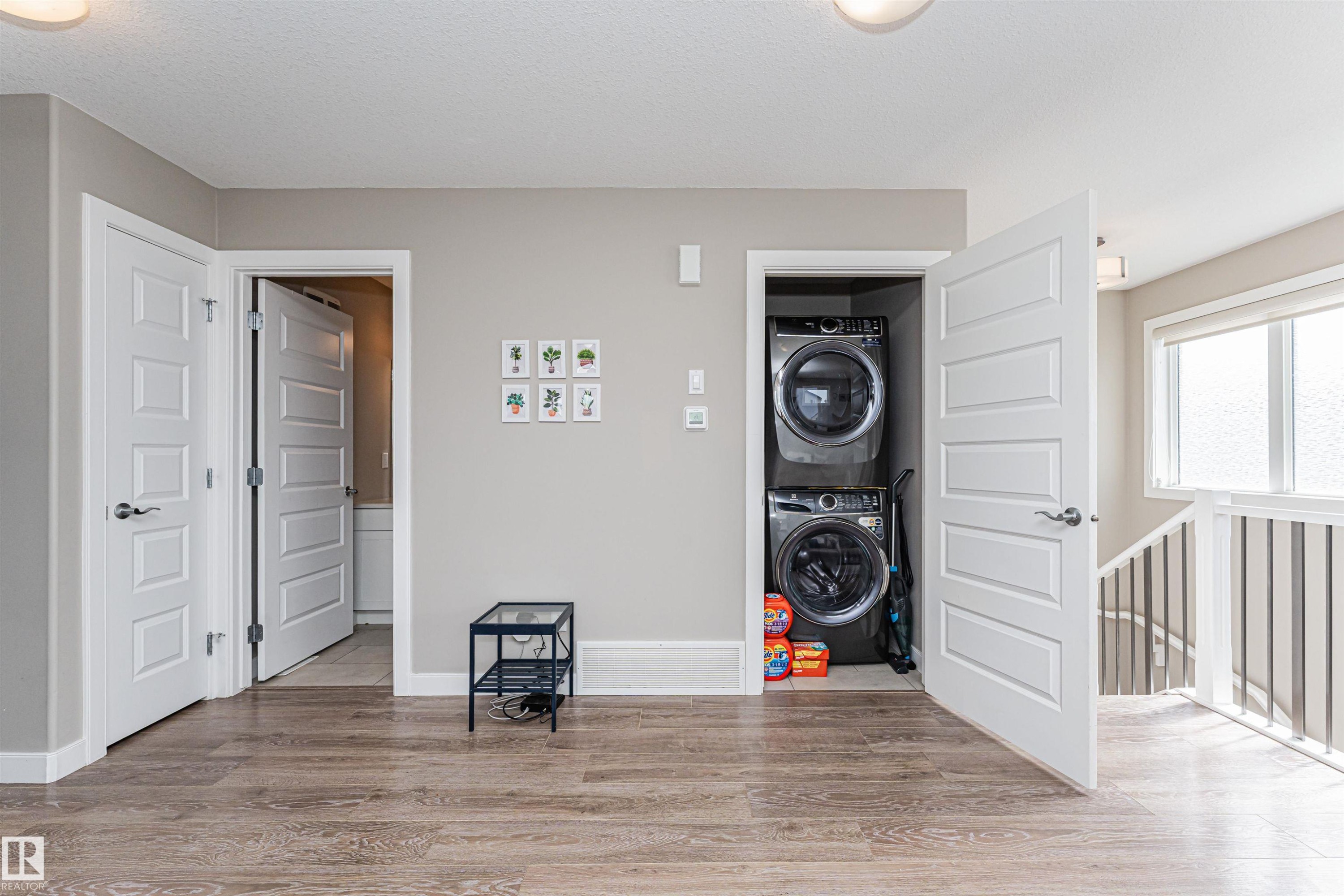 Wood-finish flooring throughout, featuring a stacked washer and dryer unit within a dedicated closet - 22124 85 Avenue Nw, Edmonton, AB - Indoor