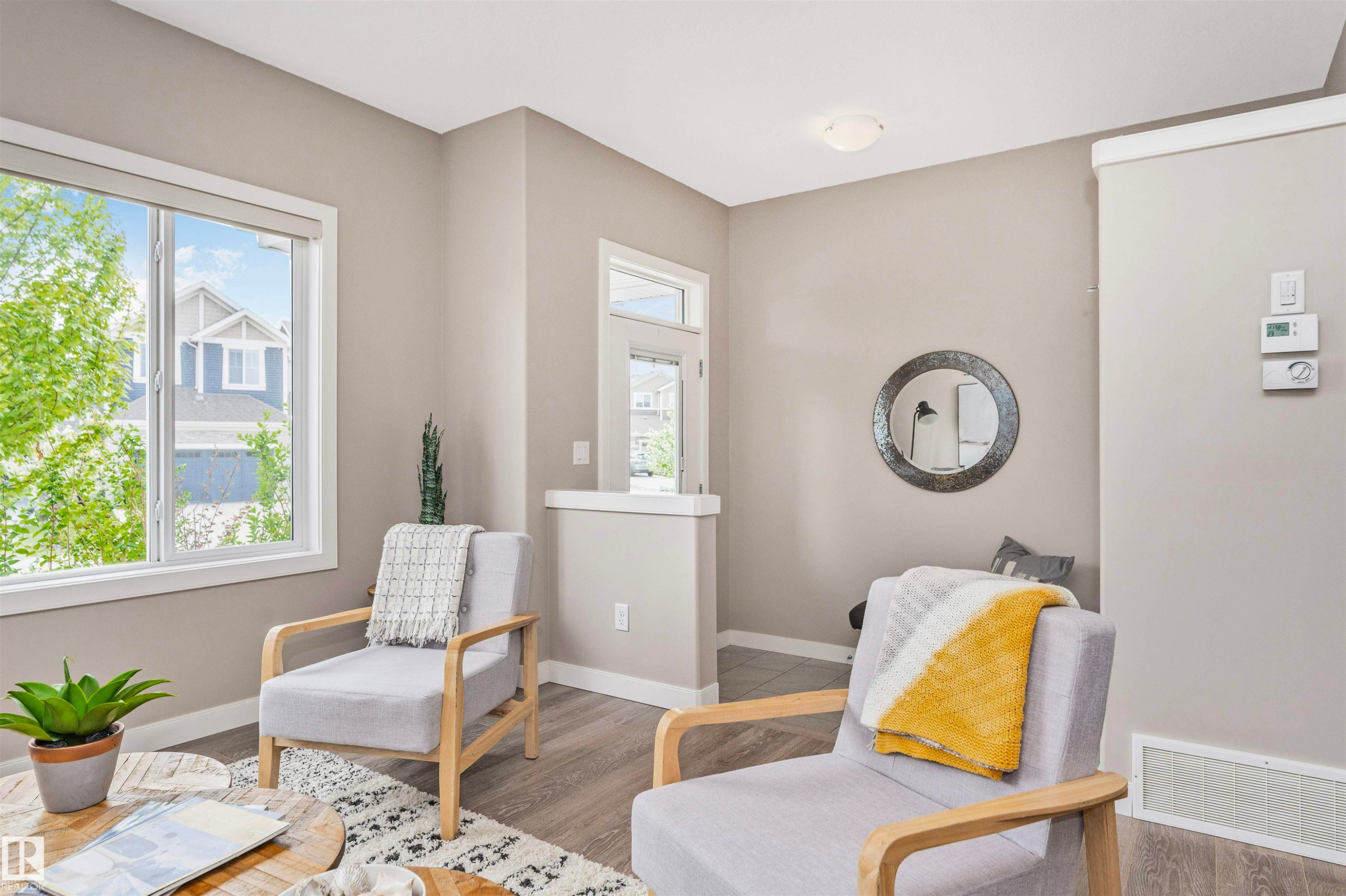 Bright interior space featuring neutral wall tones, white trim, wood-finish flooring, a contemporary flush-mount ceiling light, and prominent windows with white frames - 22124 85 Avenue Nw, Edmonton, AB - Indoor