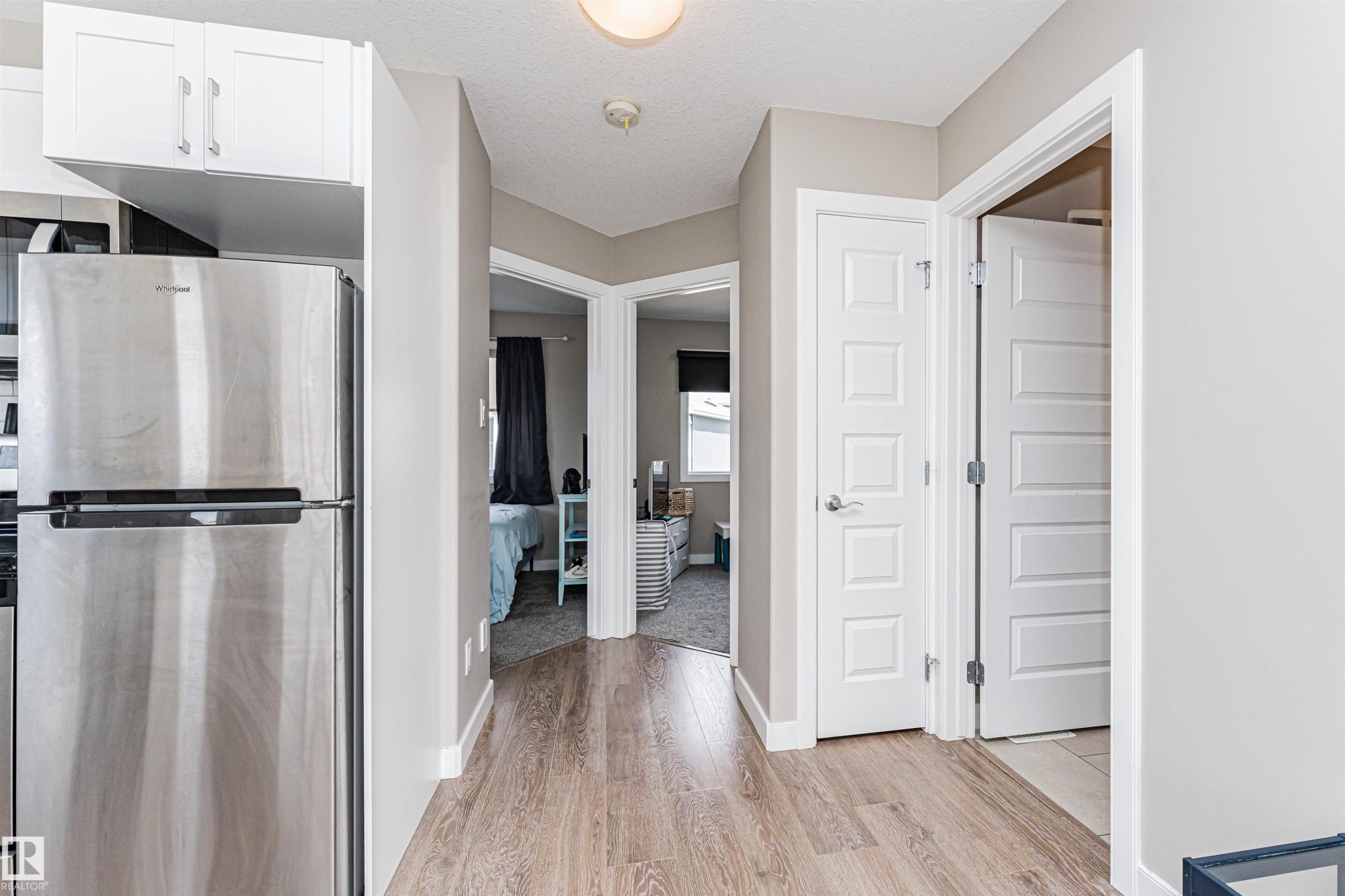 Hallway featuring wood-finish flooring and multiple white paneled doors - 22124 85 Avenue Nw, Edmonton, AB - Indoor