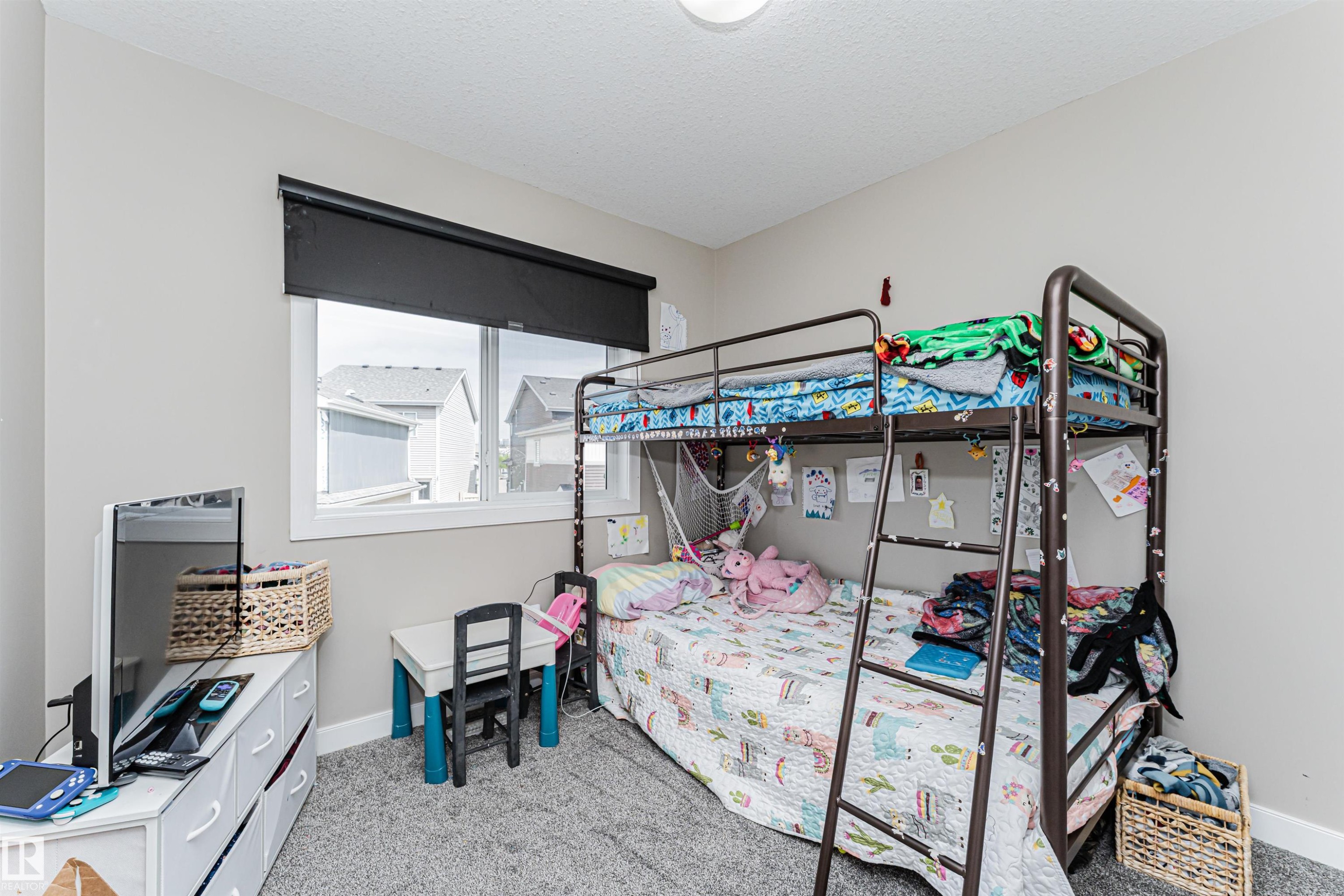 Plush gray carpet flooring compliments neutral wall tones in this room featuring a single window with a dark roller shade - 22124 85 Avenue Nw, Edmonton, AB - Indoor Photo Showing Bedroom