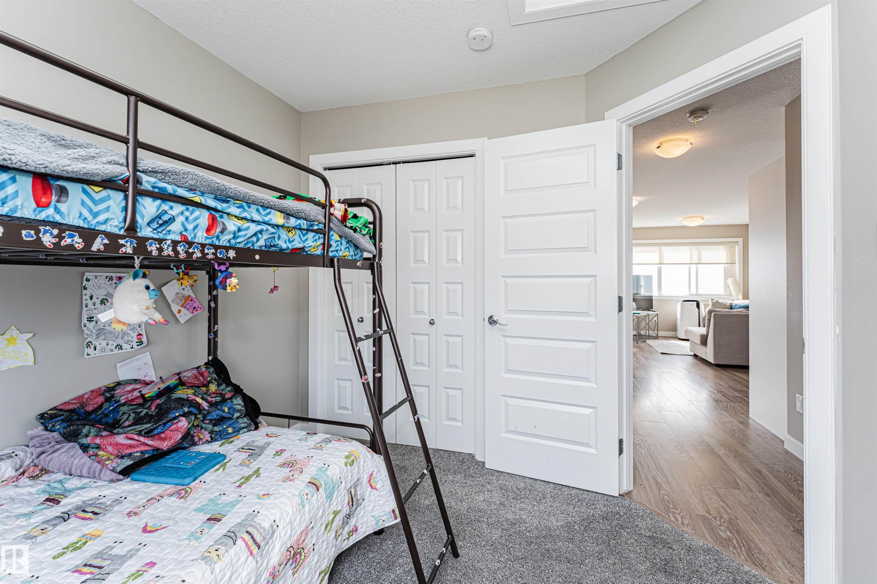 Carpeted room featuring a closet with bi-fold doors and a five-panel interior door opening to a hallway with wood-finish flooring - 22124 85 Avenue Nw, Edmonton, AB - Indoor Photo Showing Bedroom