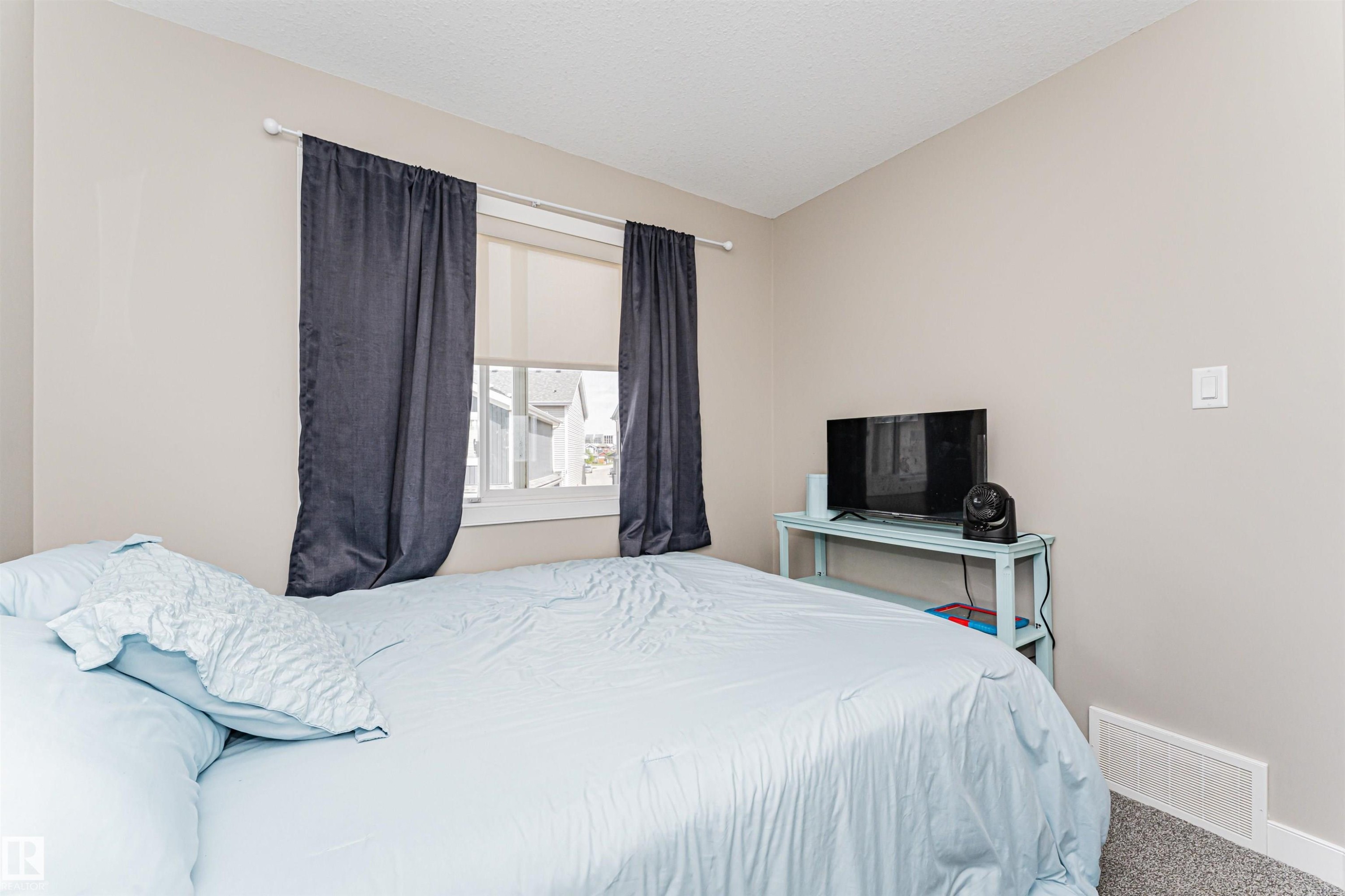 Wall-to-wall carpeting, neutral wall palette, white trim, single window, and a ceiling-mounted light fixture - 22124 85 Avenue Nw, Edmonton, AB - Indoor Photo Showing Bedroom