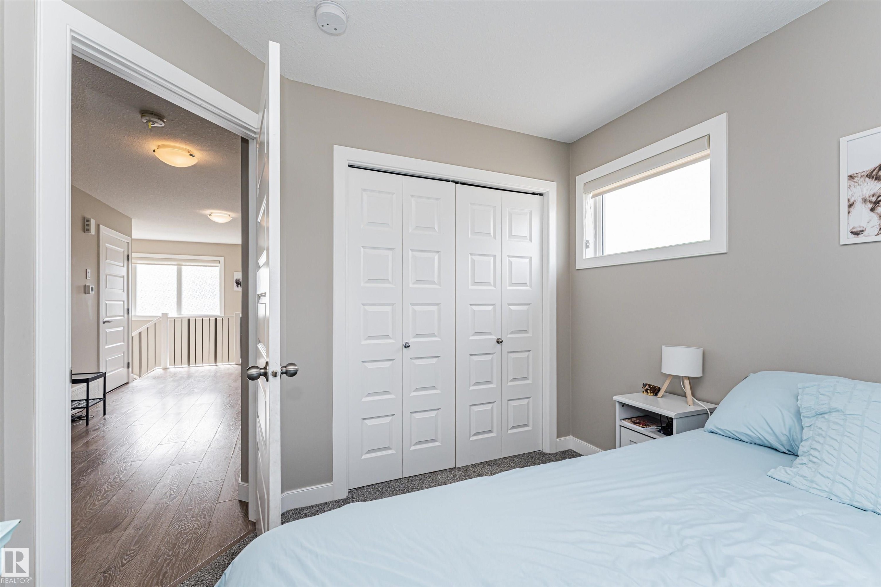 Carpeted room with a bi-fold closet, a white trimmed window, and neutral painted walls - 22124 85 Avenue Nw, Edmonton, AB - Indoor Photo Showing Bedroom