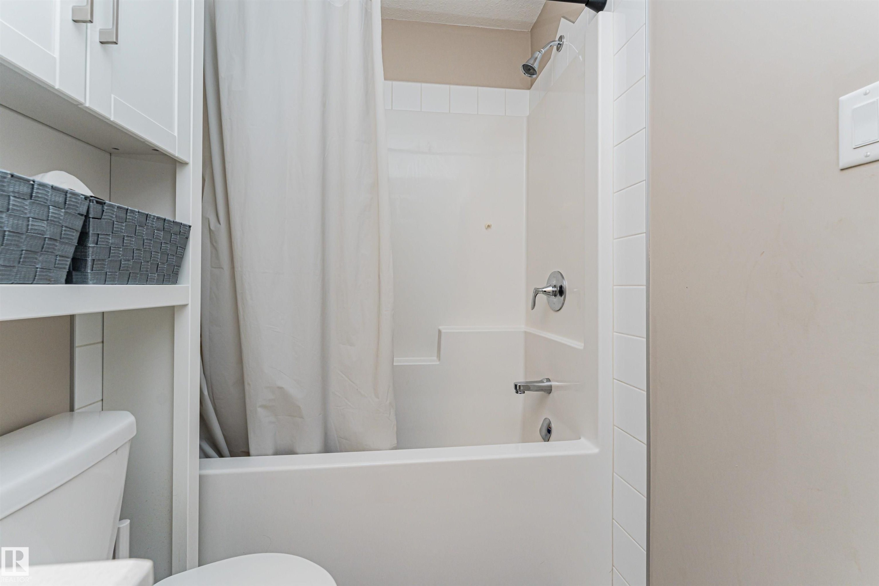 Bathroom featuring a white bathtub and shower combination with chrome fixtures - 22124 85 Avenue Nw, Edmonton, AB - Indoor Photo Showing Bathroom