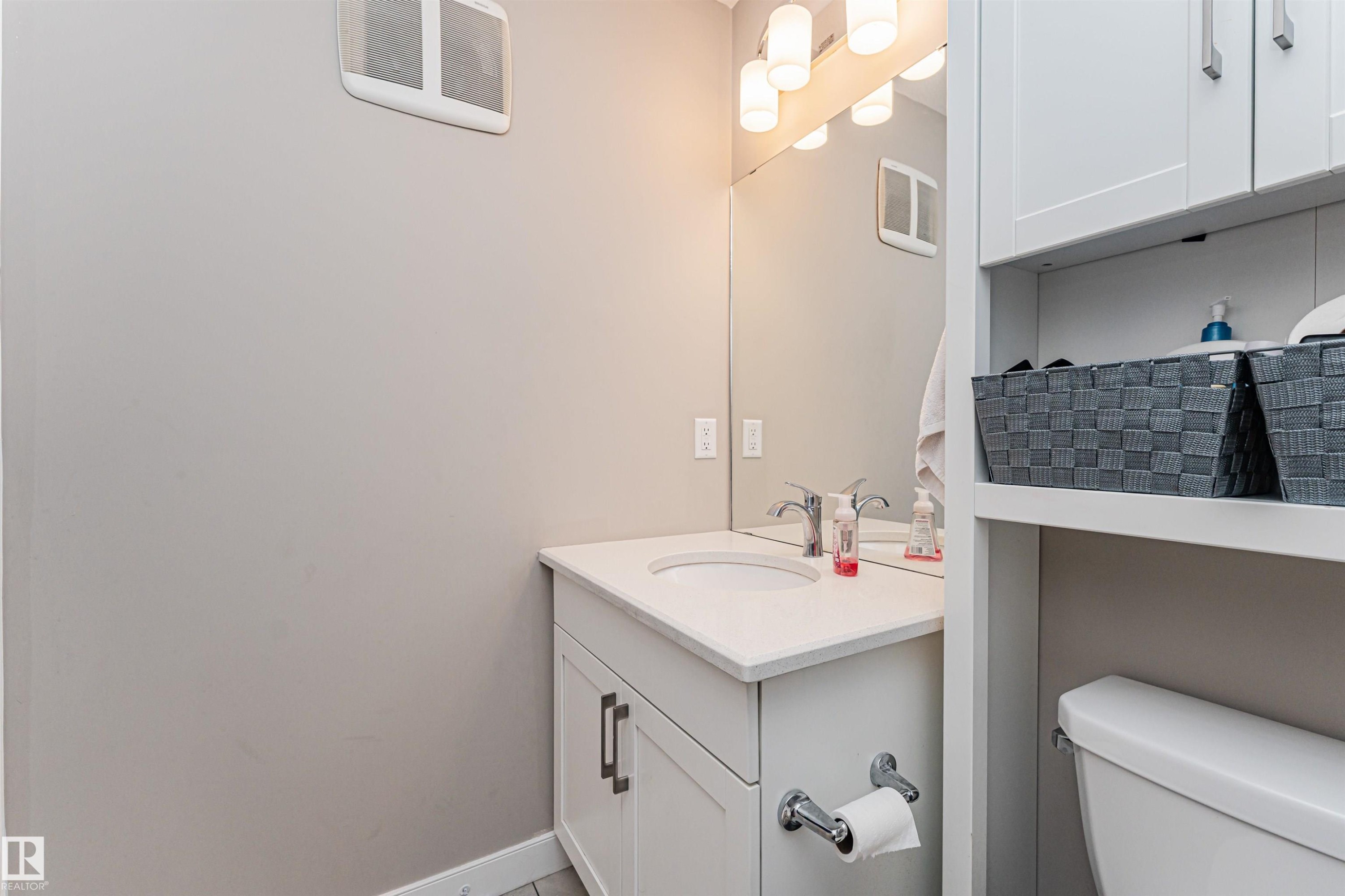 White vanity with an integrated sink, polished chrome faucet, and a wall-mounted mirror - 22124 85 Avenue Nw, Edmonton, AB - Indoor Photo Showing Bathroom