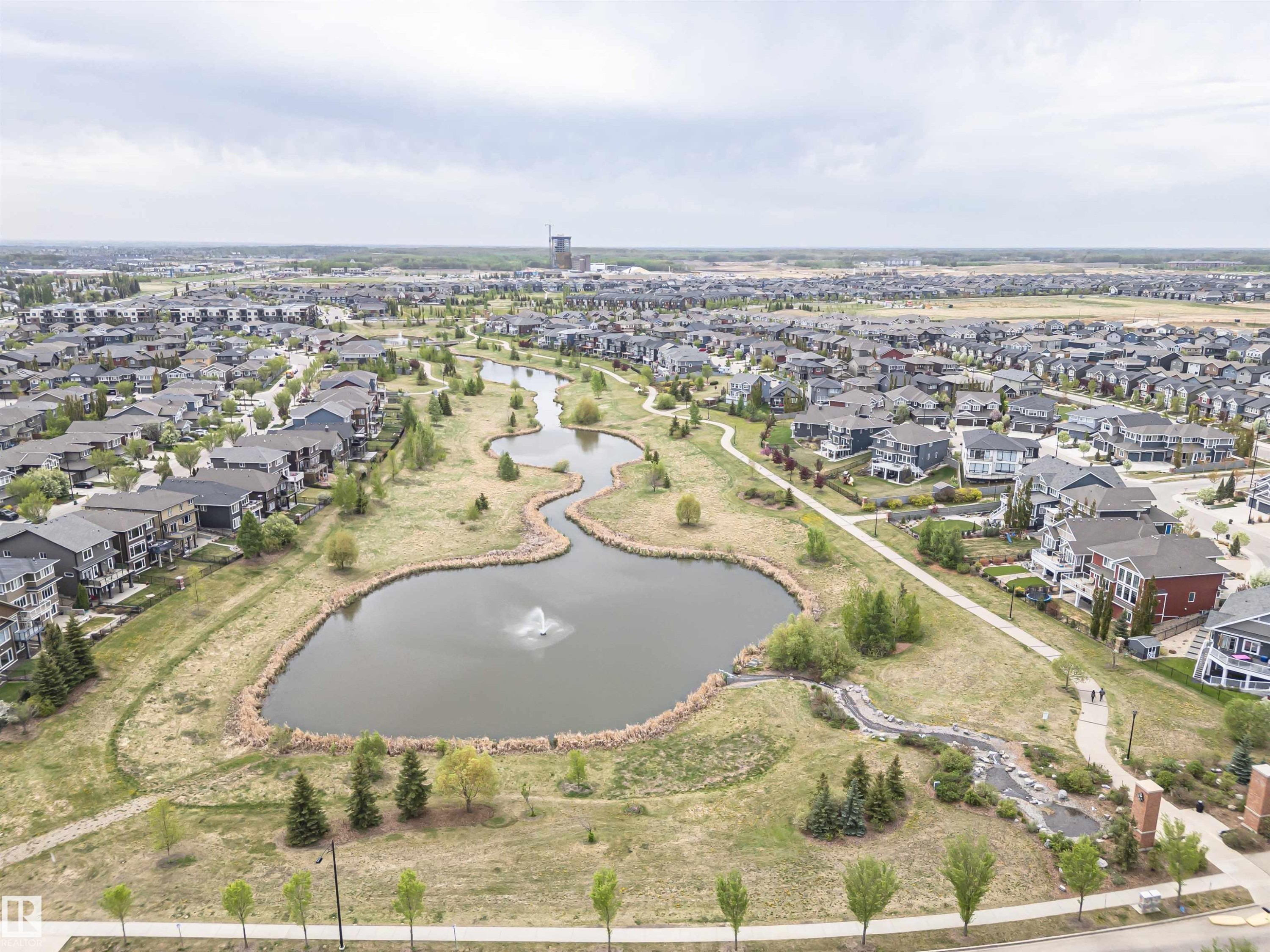 Expansive residential development featuring a central pond with a fountain, a meandering walking path system, mature and newly planted trees, and a diverse collection of single-family homes - 22124 85 Avenue Nw, Edmonton, AB - Outdoor With View