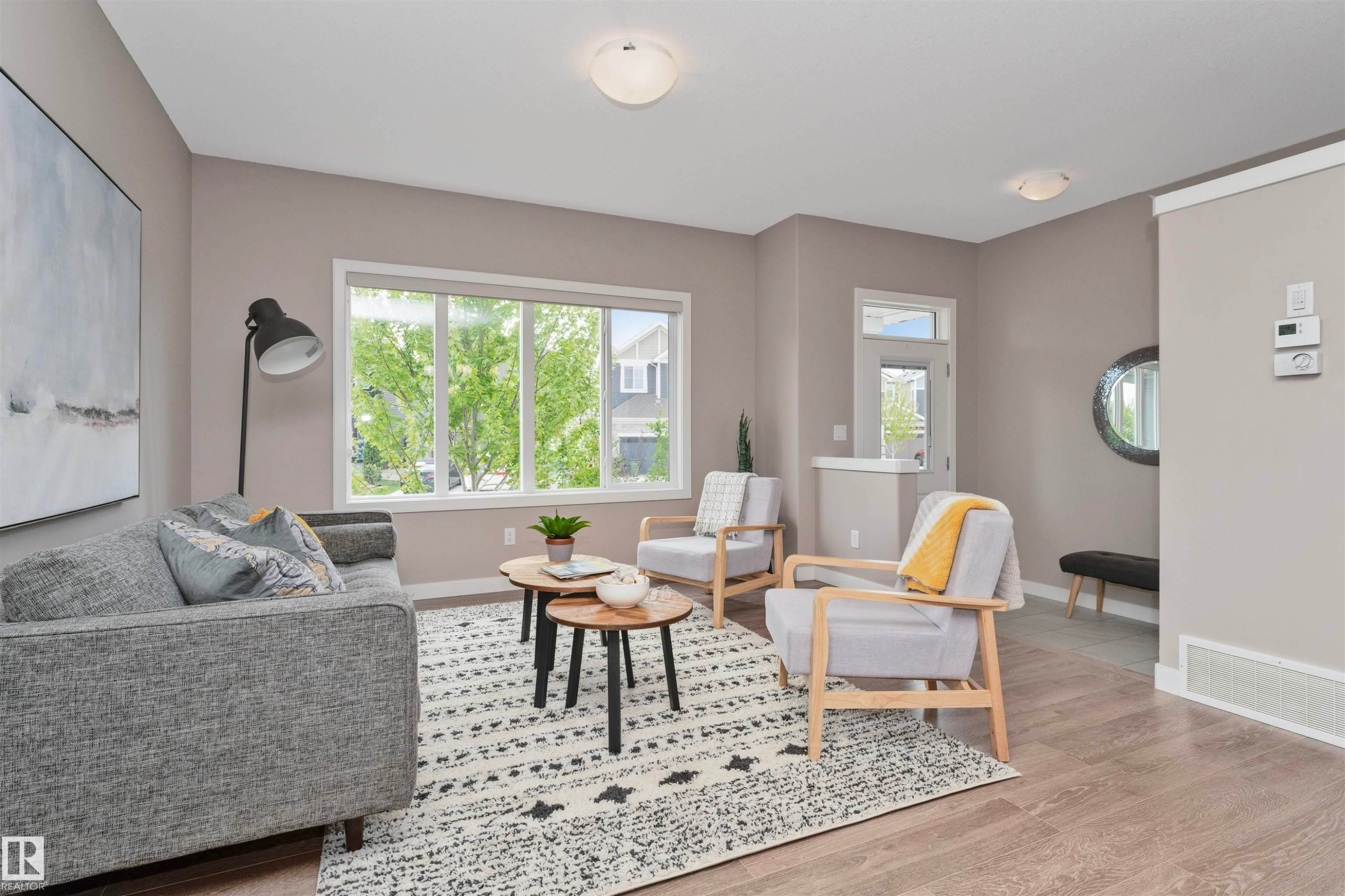 Living area featuring expansive windows, wood-finish flooring, recessed lighting, and a white trim entry door - 22124 85 Avenue Nw, Edmonton, AB - Indoor Photo Showing Living Room