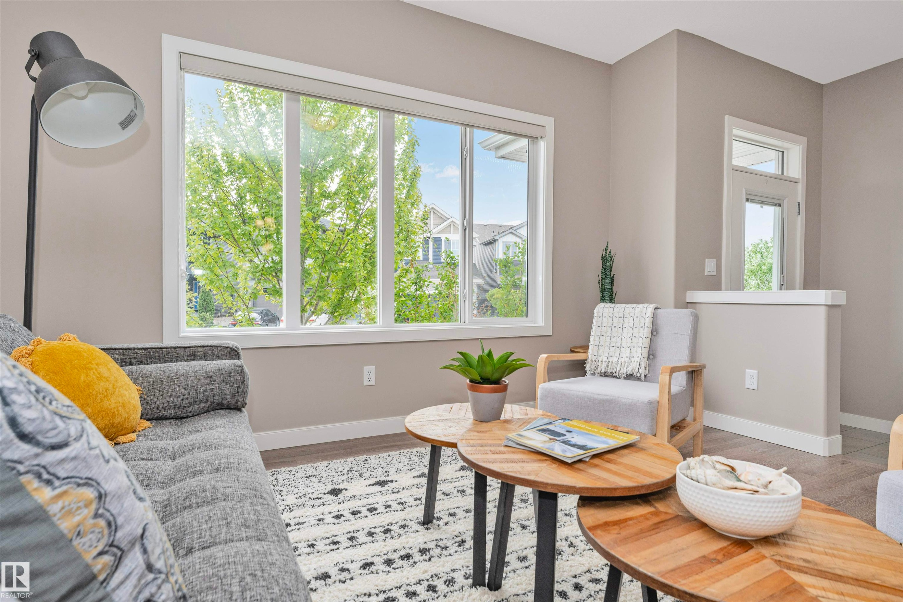 Bright living area featuring large multi-panel windows, neutral wall tones, and light wood-finish flooring - 22124 85 Avenue Nw, Edmonton, AB - Indoor Photo Showing Living Room