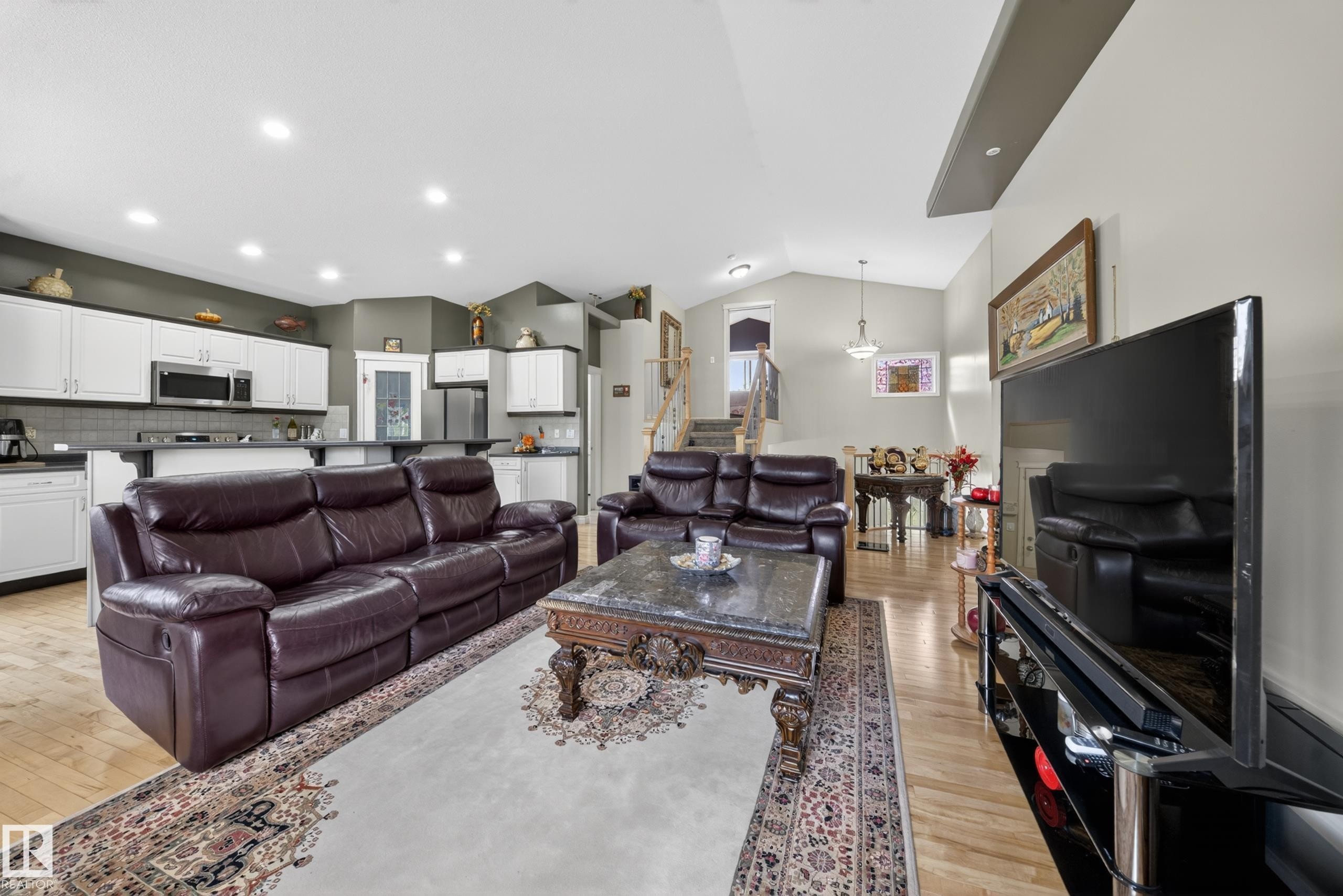 Open concept living area featuring wood-finish flooring, recessed lighting, and a vaulted ceiling - 4113 59 Street, Beaumont, AB