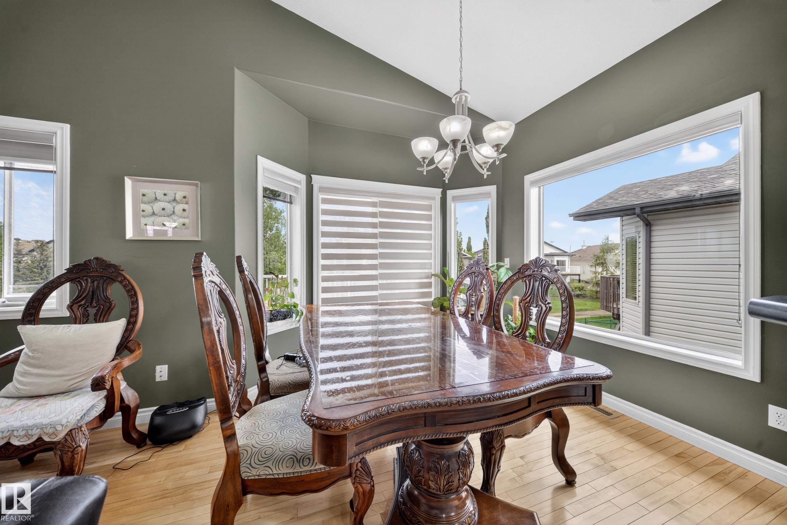 Dining area with wood-finish flooring, olive-toned walls, and a multi-pane window configuration - 4113 59 Street, Beaumont, AB