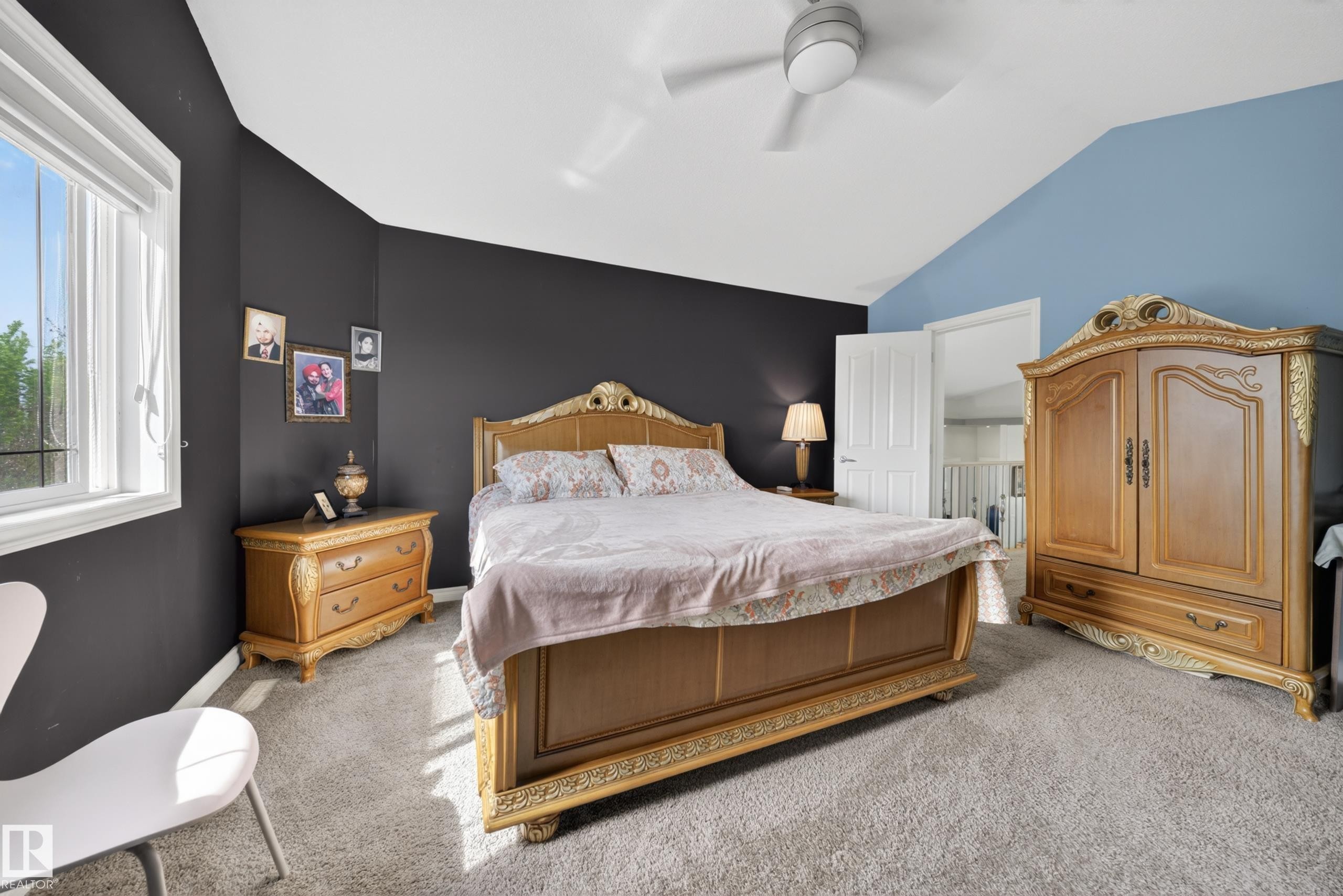 Spacious room featuring vaulted ceilings, a large window, a ceiling fan, plush gray carpeting, and a white interior door - 4113 59 Street, Beaumont, AB