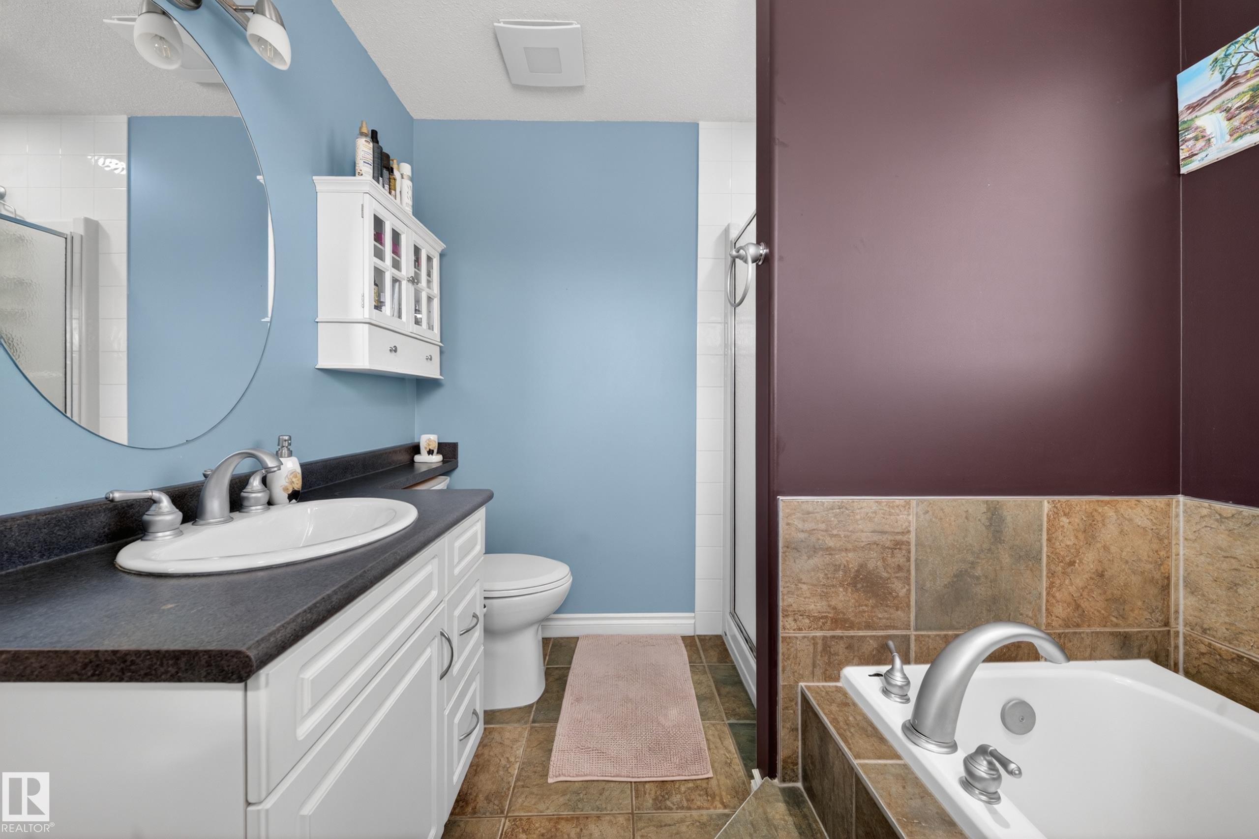 Bathroom featuring a white vanity with dark countertop, oval undermount sink, and brushed chrome faucet - 4113 59 Street, Beaumont, AB
