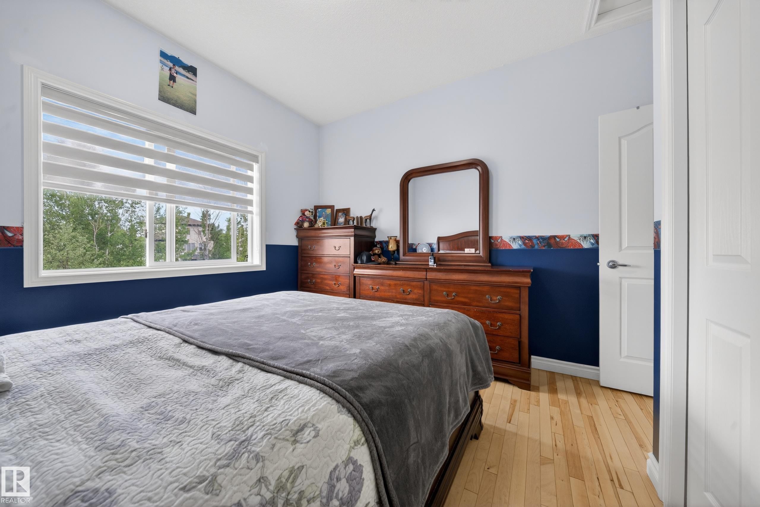 Bedroom featuring light wood-finish flooring, a white window frame, and white trim - 4113 59 Street, Beaumont, AB