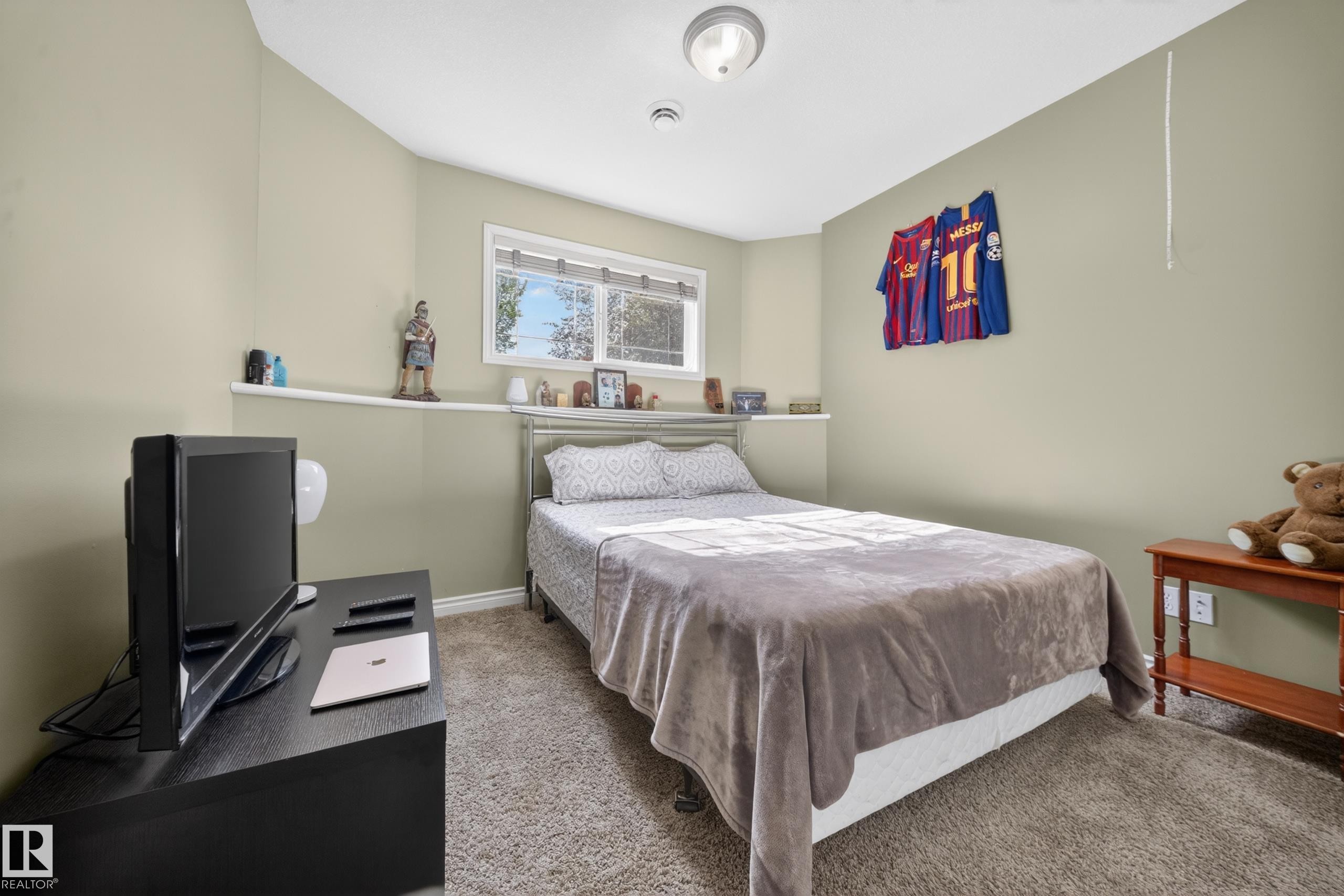 Carpeted room featuring a window with white blinds, a built-in shelf below the window, and a flush-mount ceiling light fixture - 4113 59 Street, Beaumont, AB