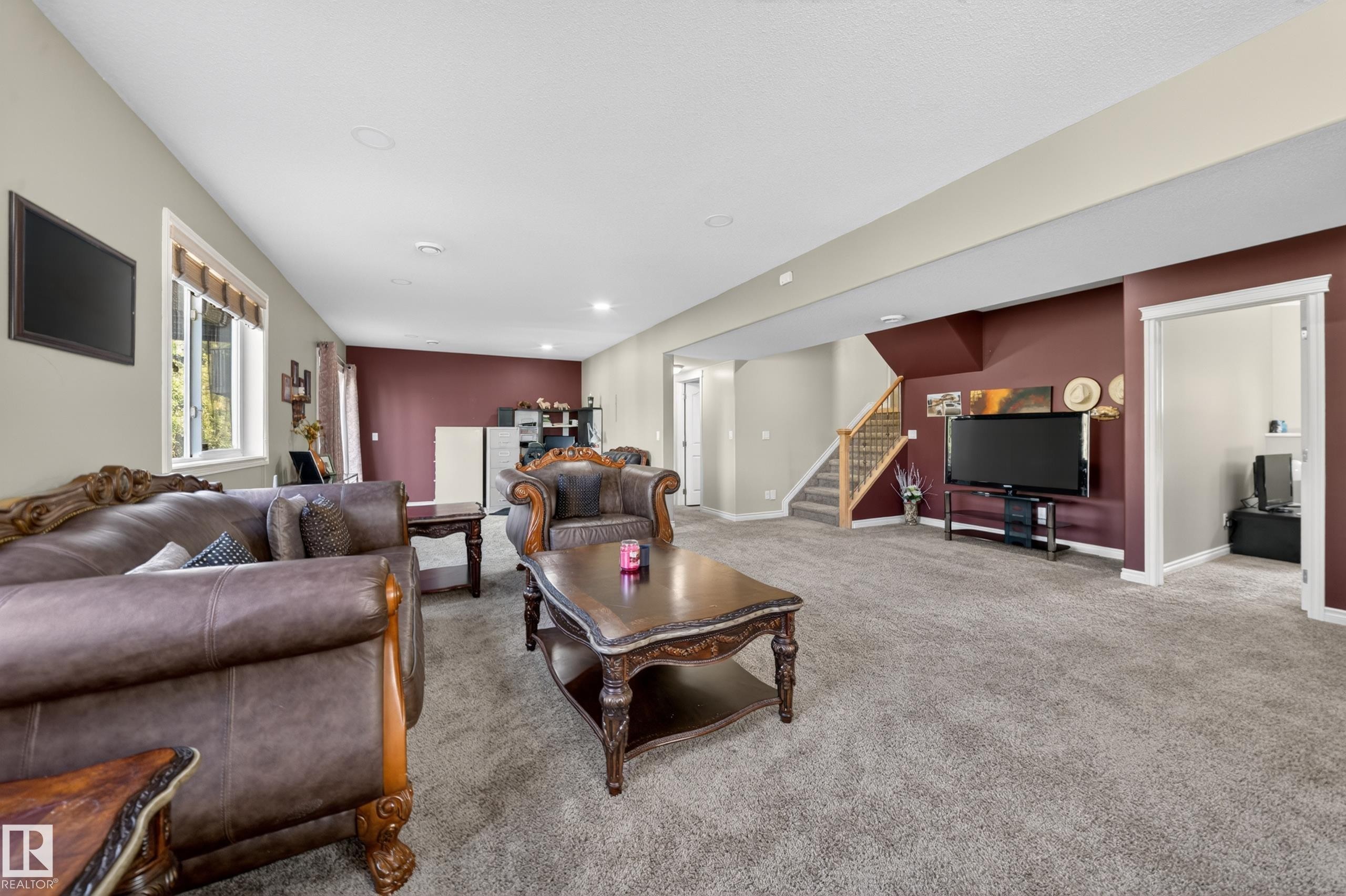 Spacious lower-level area featuring plush carpeting, recessed lighting, and a prominent accent wall - 4113 59 Street, Beaumont, AB