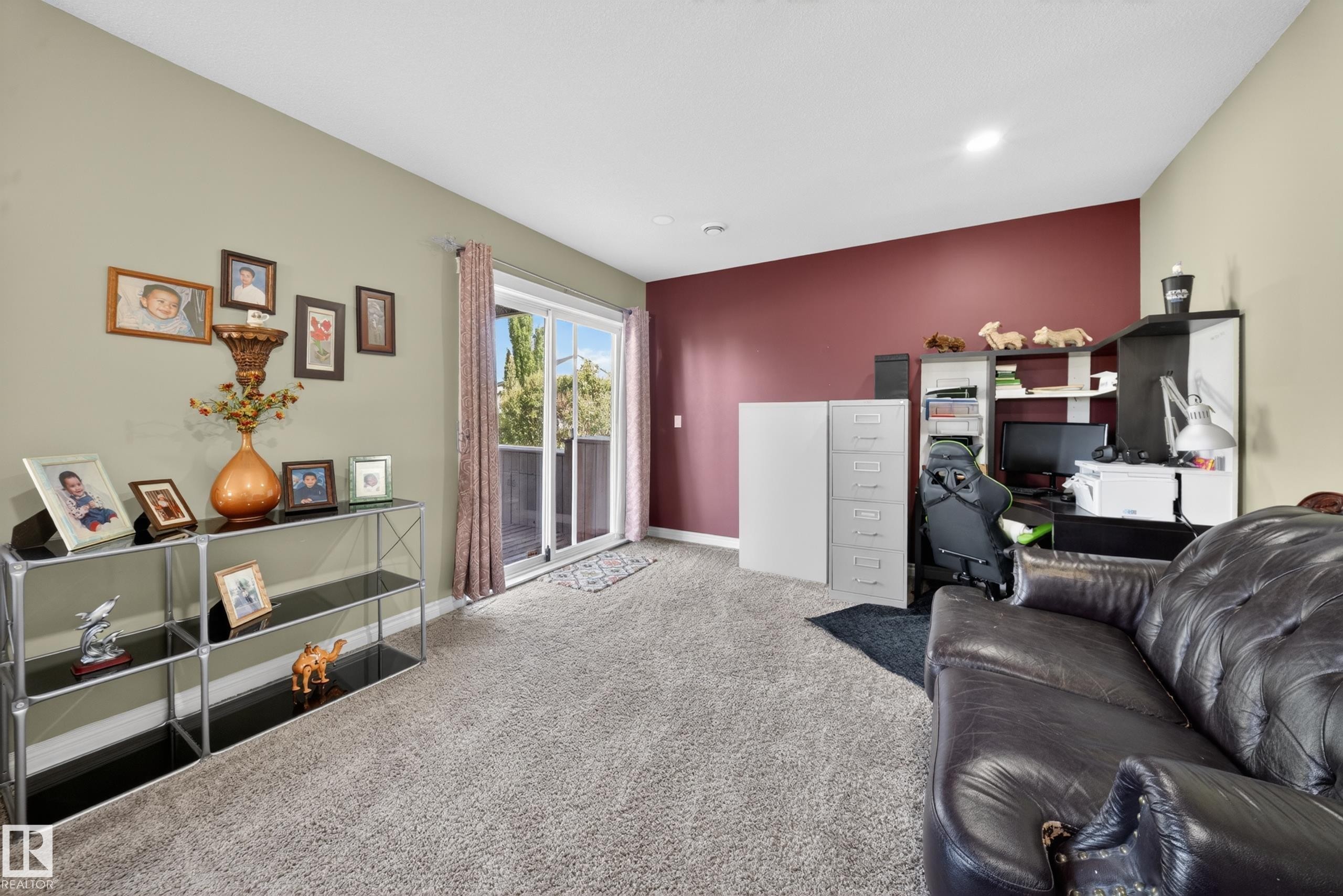 Carpeted interior space featuring a sliding glass door with exterior access, recessed ceiling lighting, and a contrasting accent wall - 4113 59 Street, Beaumont, AB