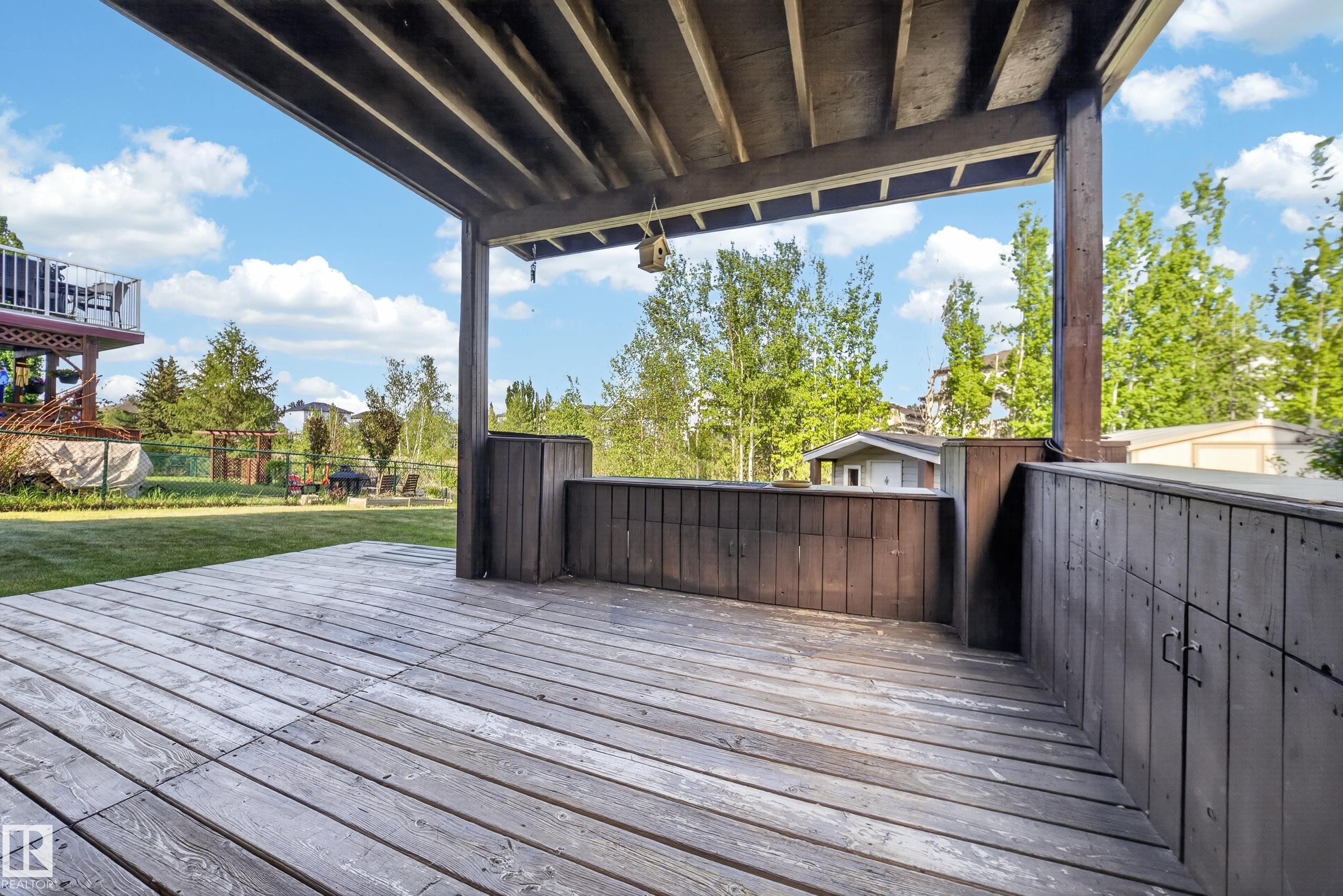 Expansive covered wood-finish deck with built-in storage and railing - 4113 59 Street, Beaumont, AB