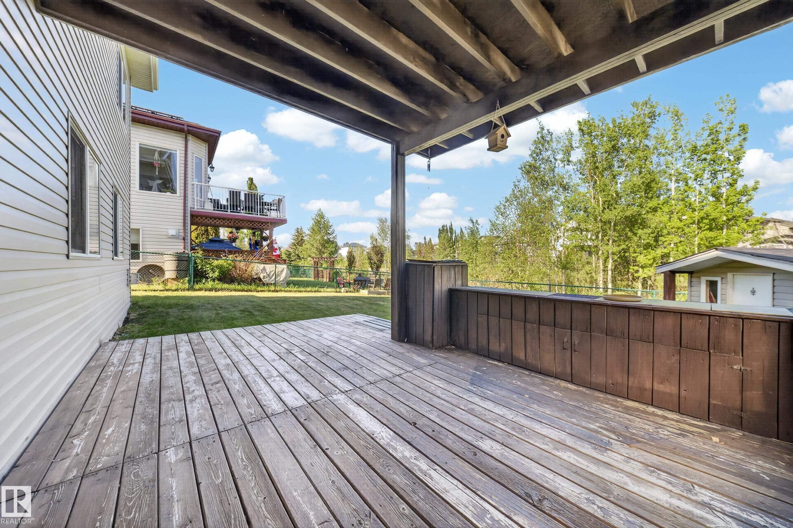 Covered wooden deck with slatted flooring and a built-in privacy wall - 4113 59 Street, Beaumont, AB